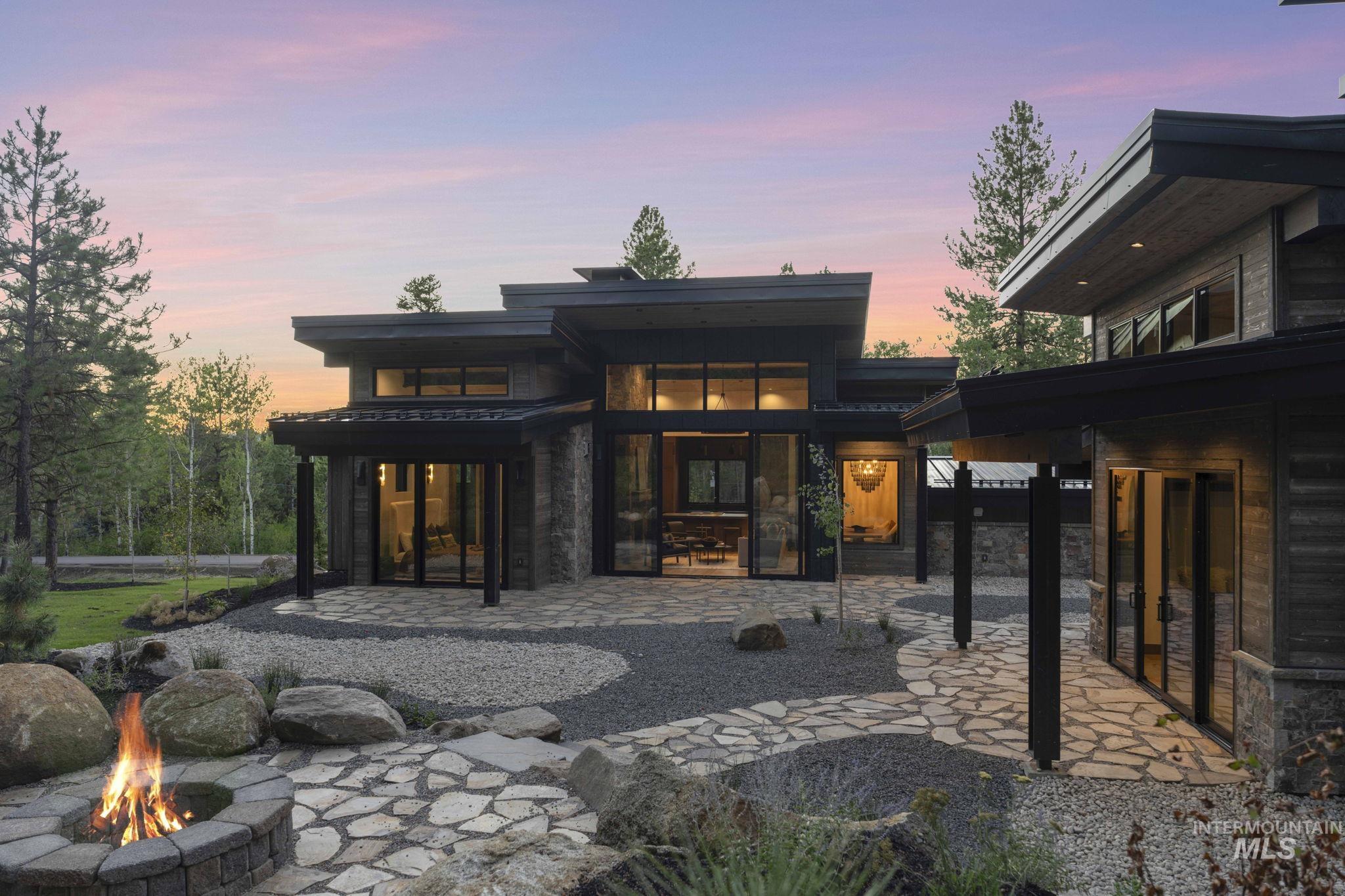 Back of property with a patio, a fire pit, and stone siding