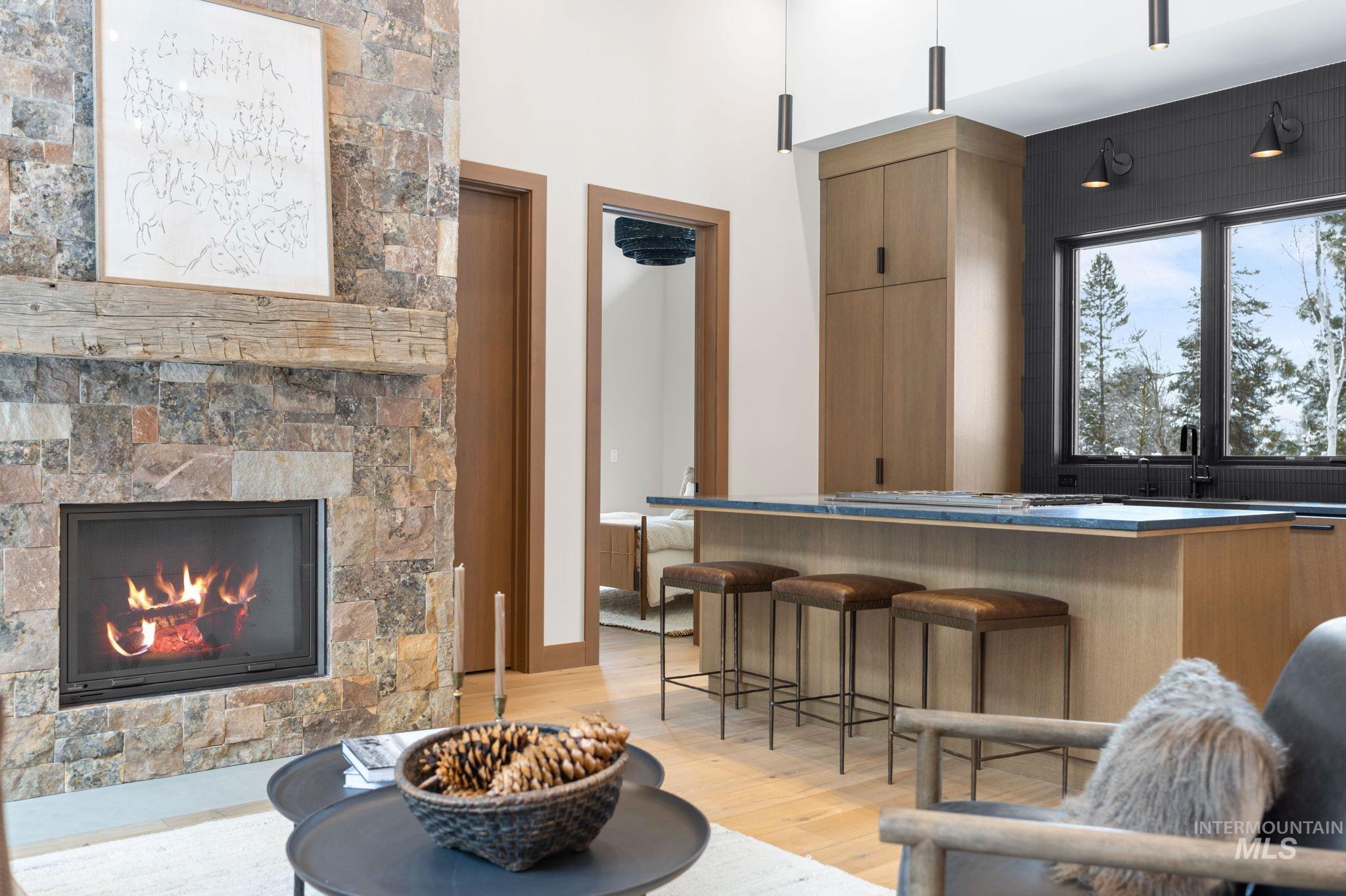 Bar area with brown cabinets, a glass covered fireplace, light wood-style floors, dark countertops, and modern cabinets