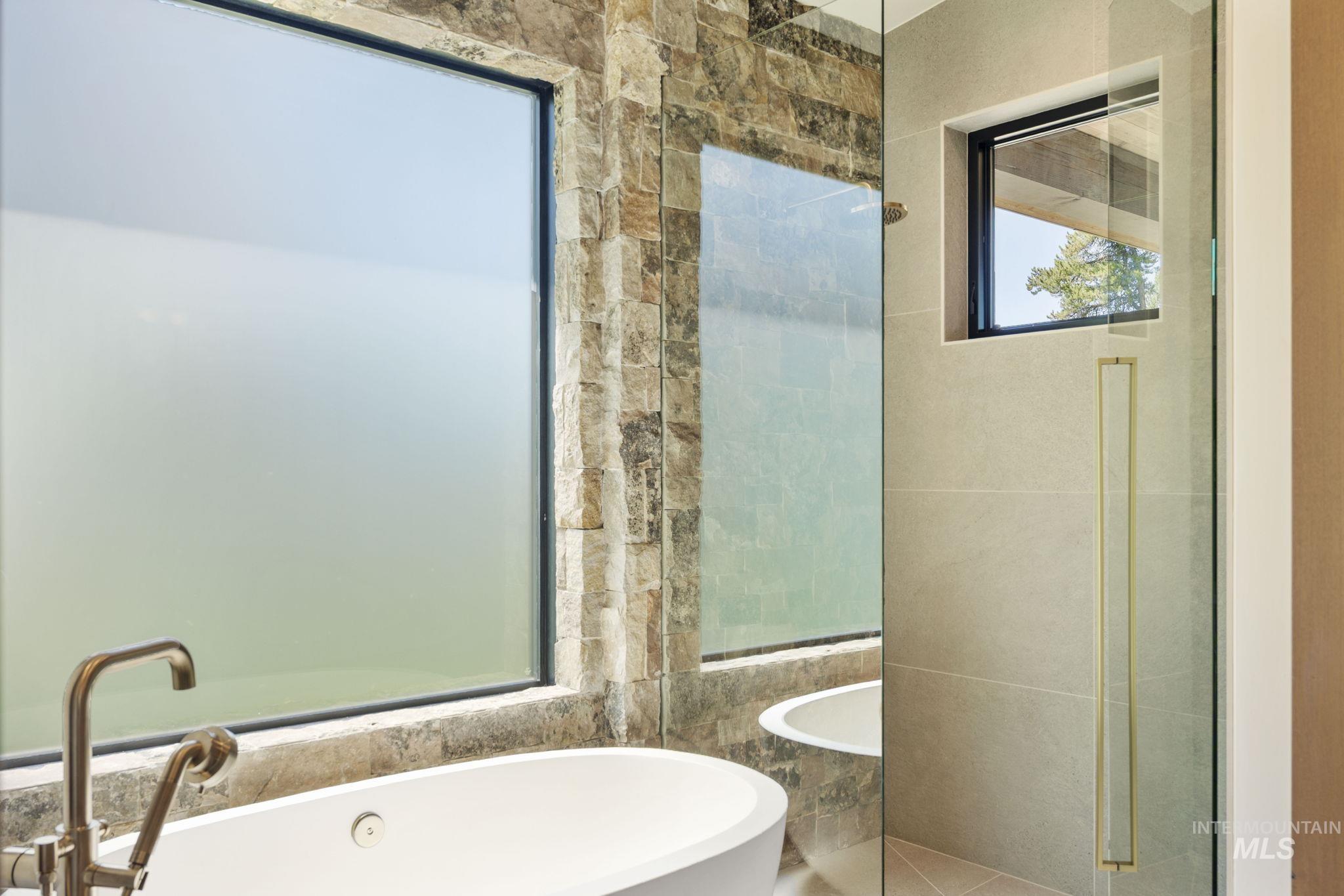 Full bath featuring a freestanding bath, tile walls, and a shower stall