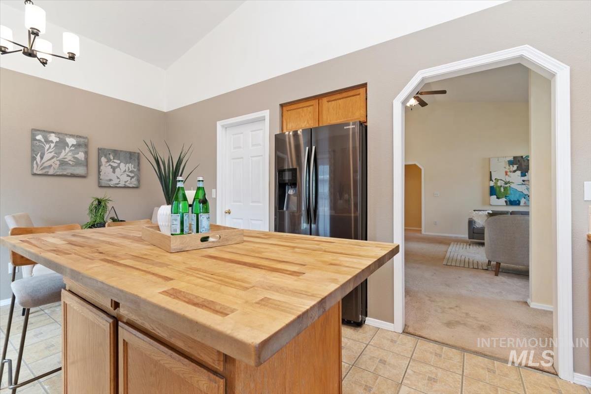 Kitchen featuring wooden counters, arched walkways, lofted ceiling, a kitchen island, and pendant lighting