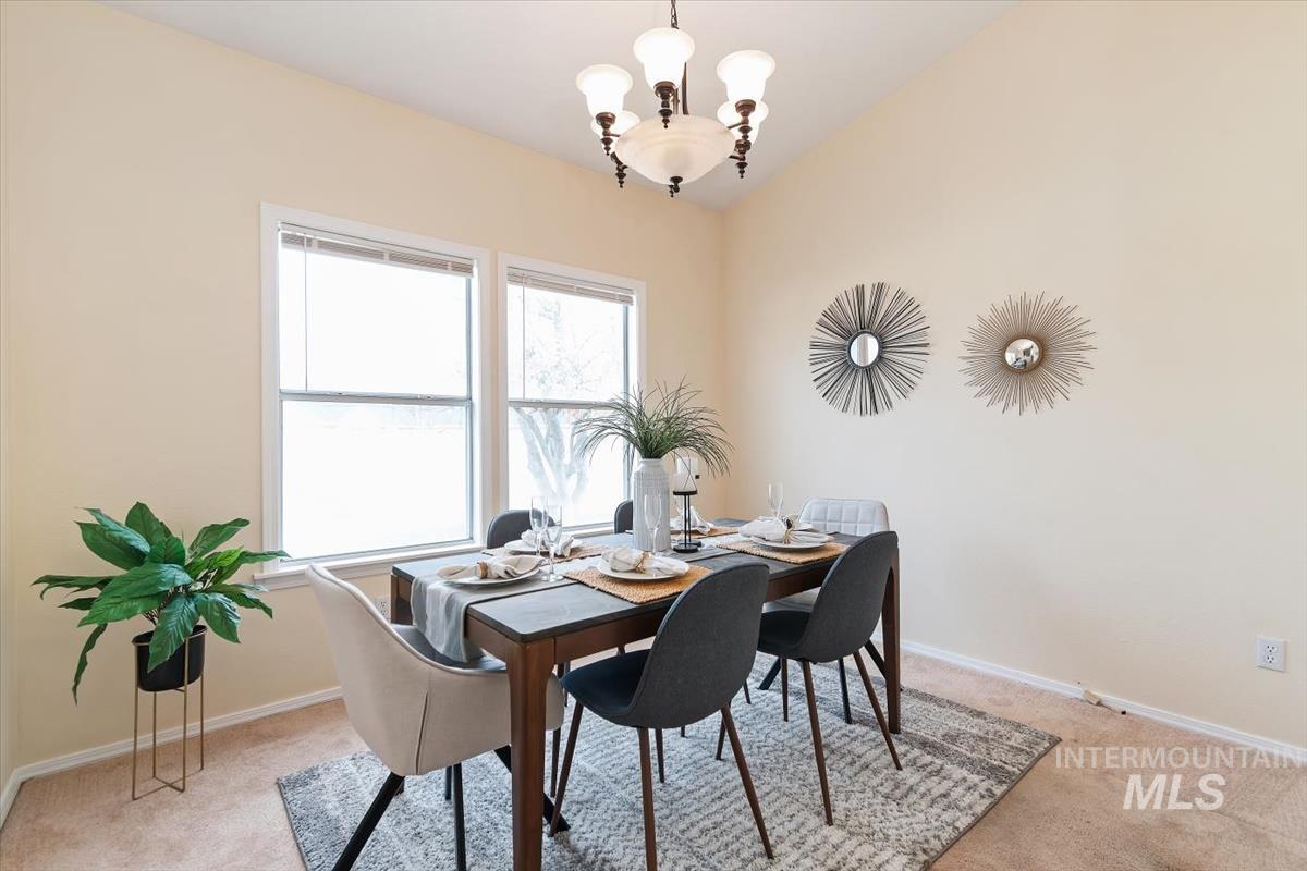 Dining room with light carpet and a chandelier