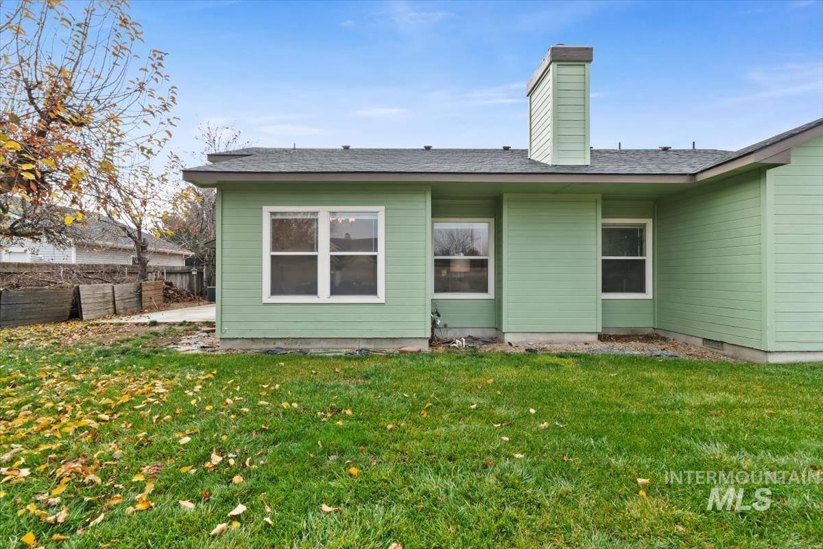 Back of house with a chimney, a patio area, and a shingled roof