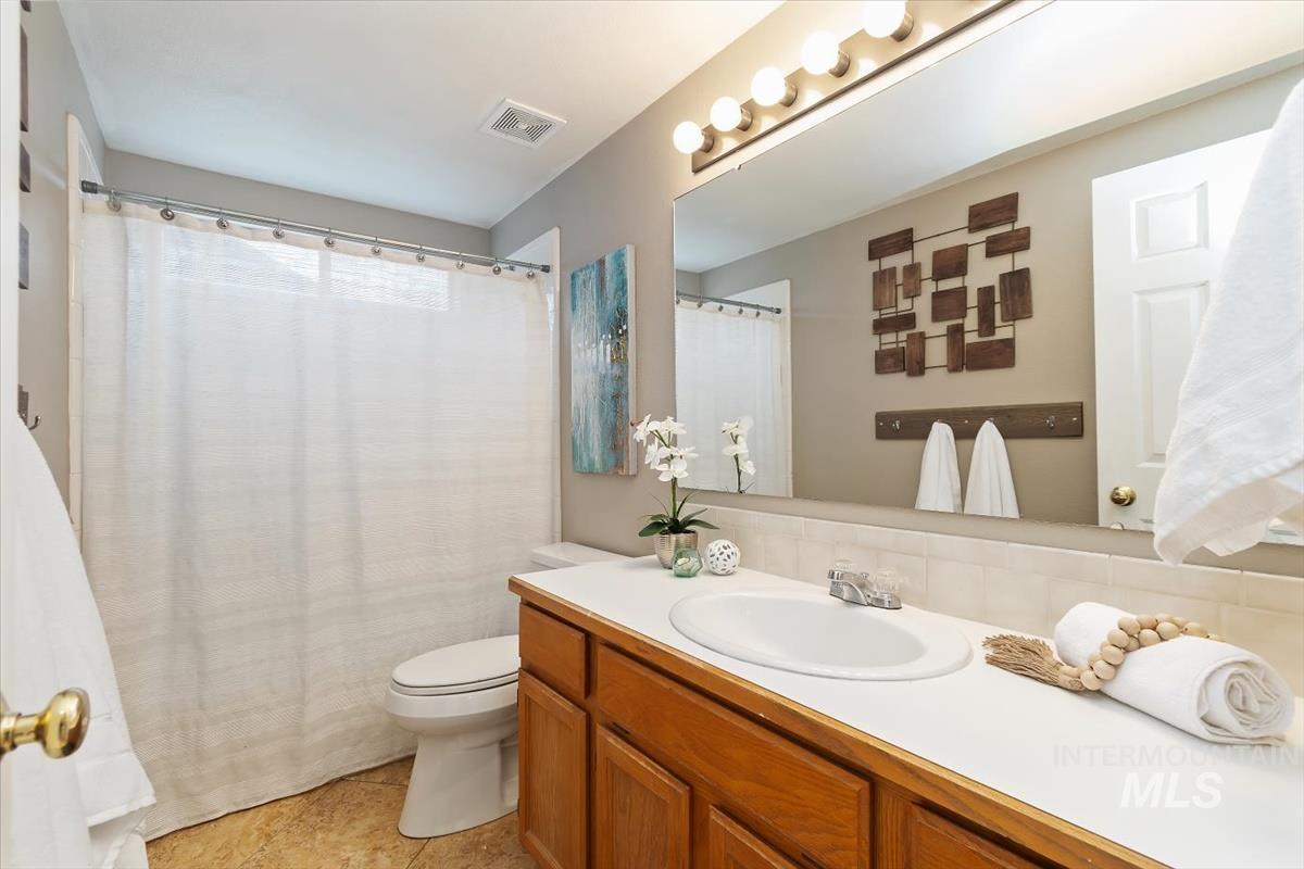 Full bath featuring a shower with curtain, vanity, and tasteful backsplash