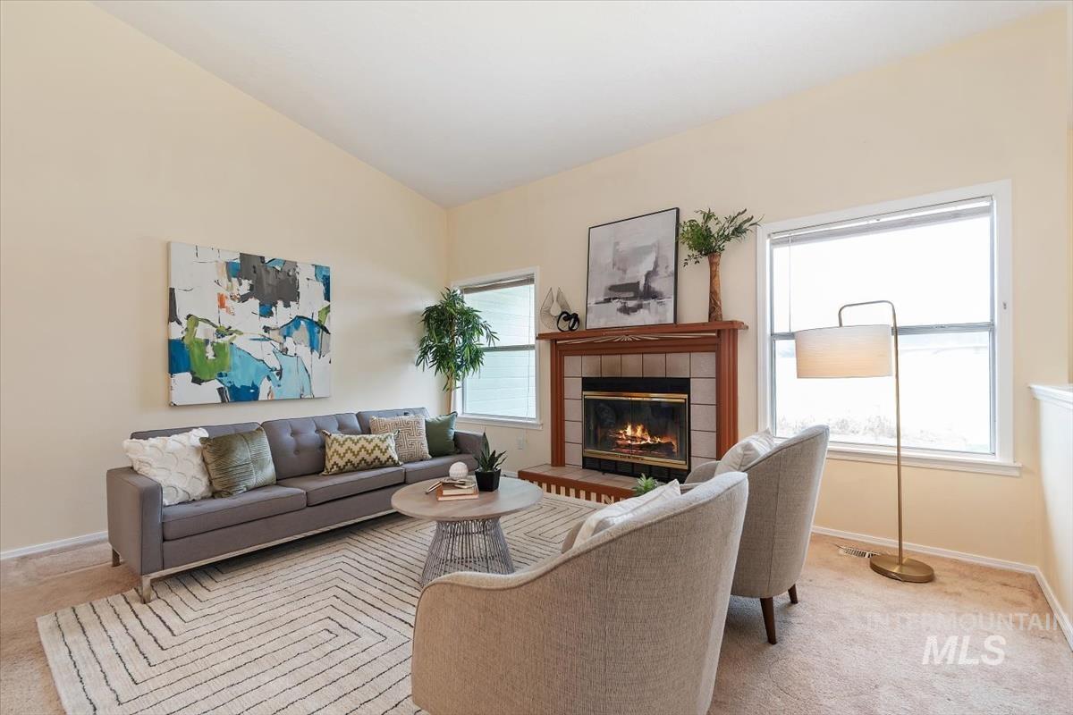 Living room featuring light carpet, lofted ceiling, and a tiled fireplace