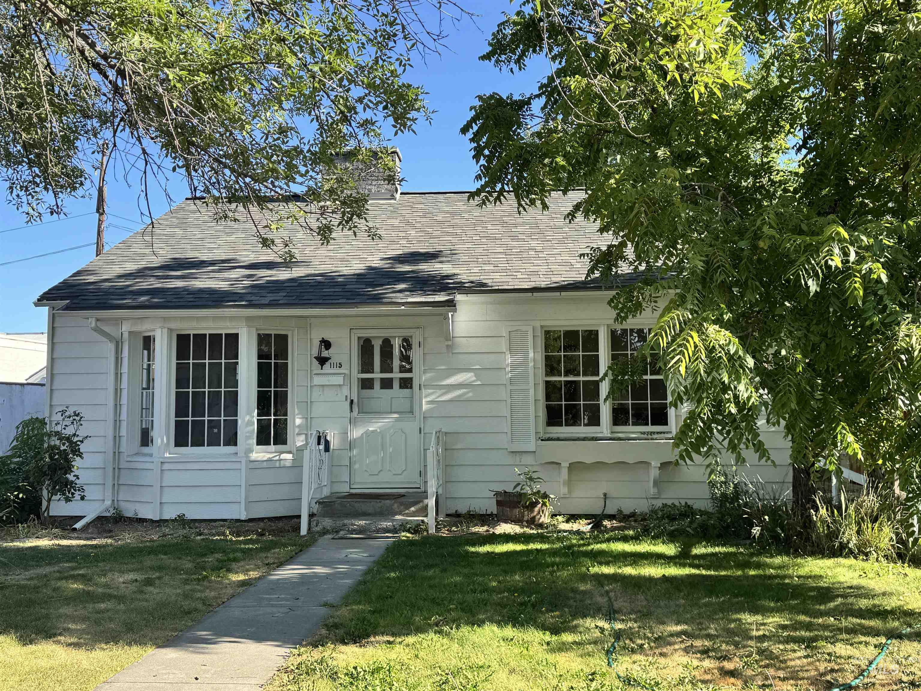 Bungalow-style house with a front yard, a shingled roof, and a chimney