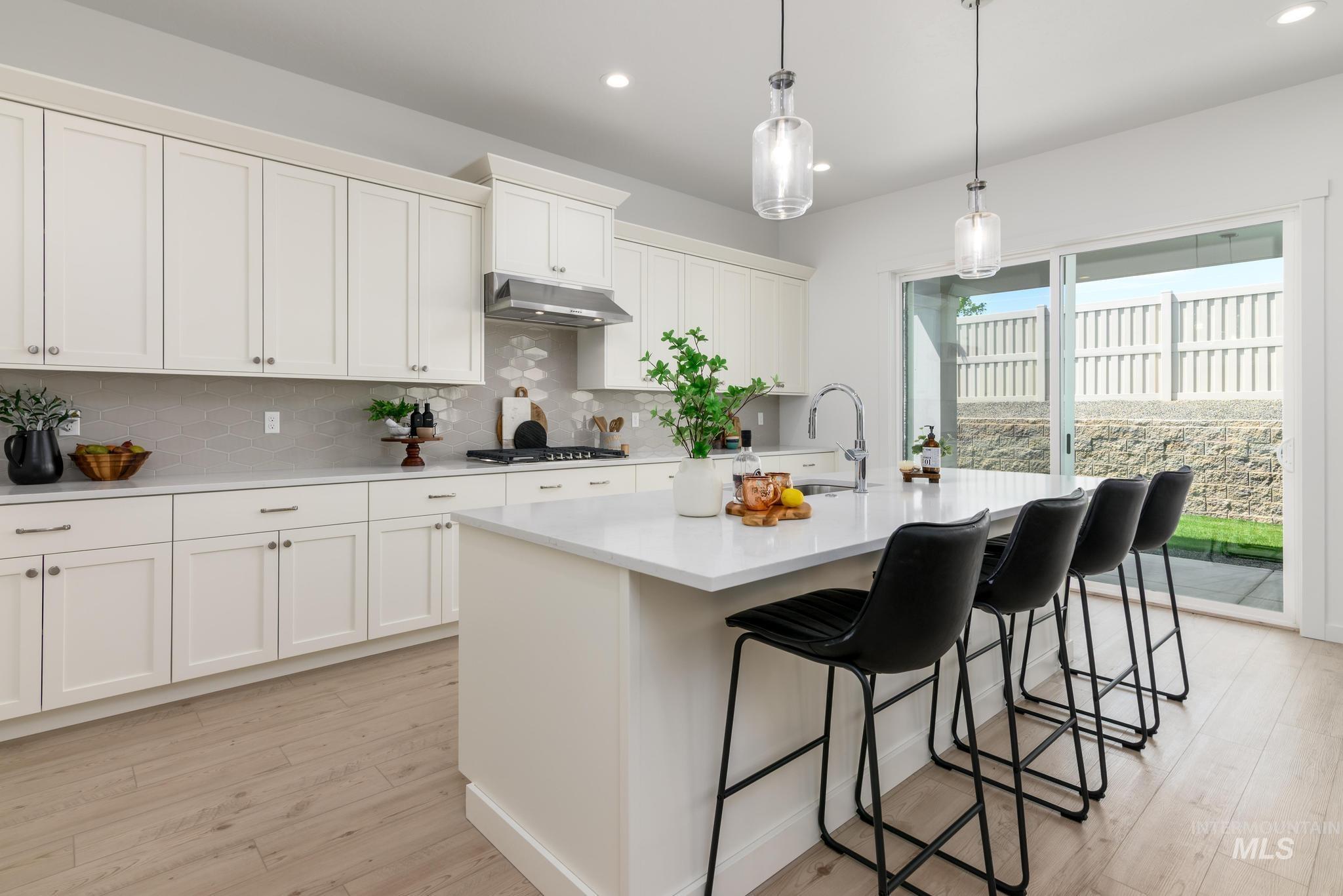 Kitchen with light wood finished floors, light countertops, a kitchen breakfast bar, tasteful backsplash, and recessed lighting
