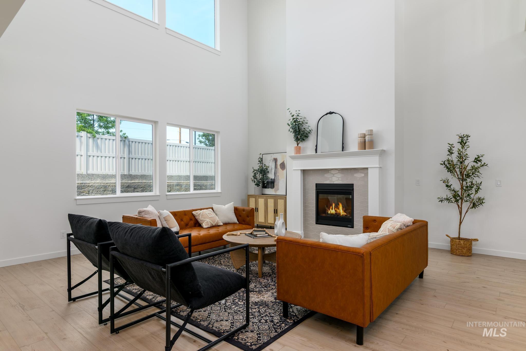 Living room featuring a tile fireplace, a towering ceiling, and light wood-type flooring