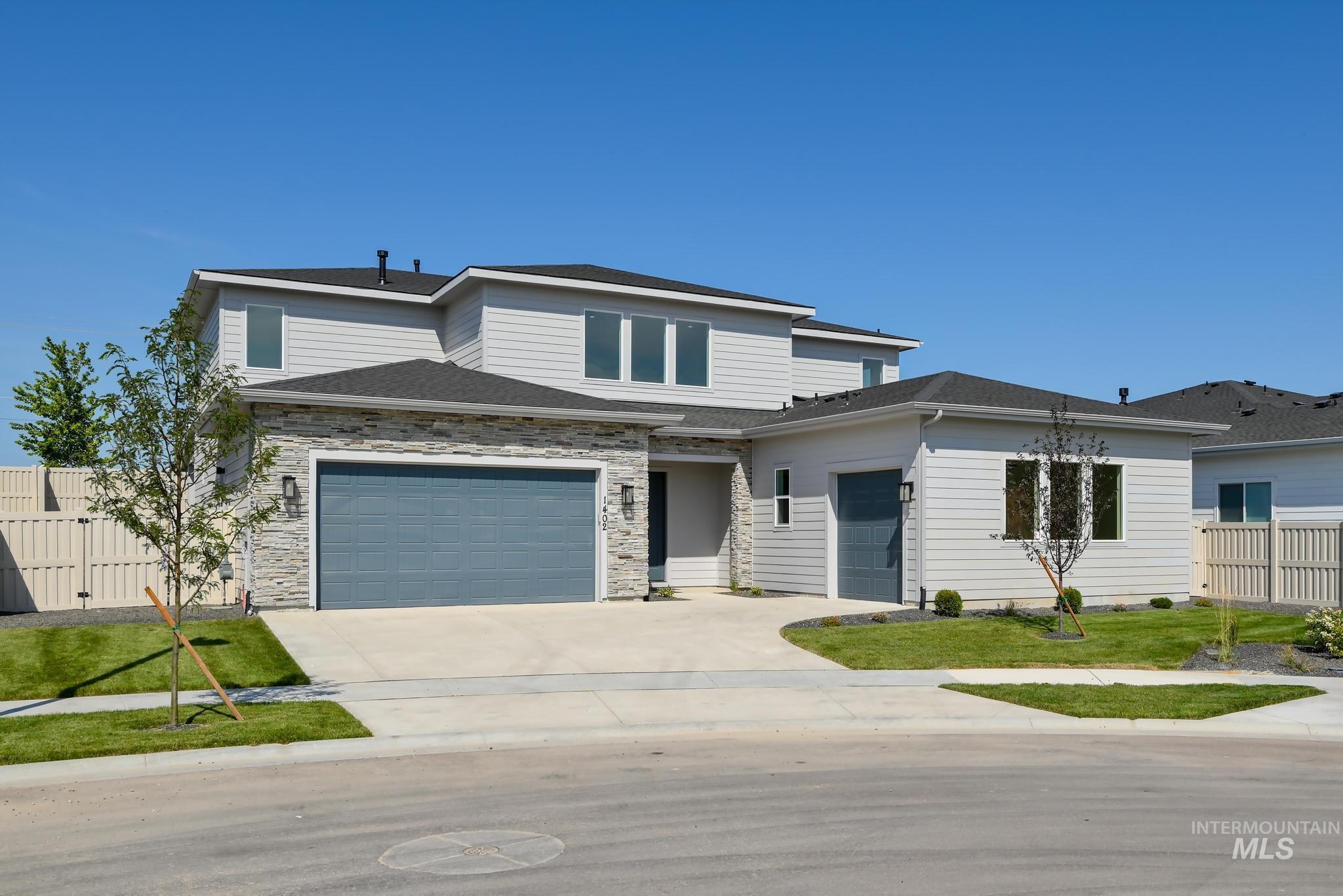 Prairie-style house with concrete driveway, an attached garage, stone siding, and roof with shingles