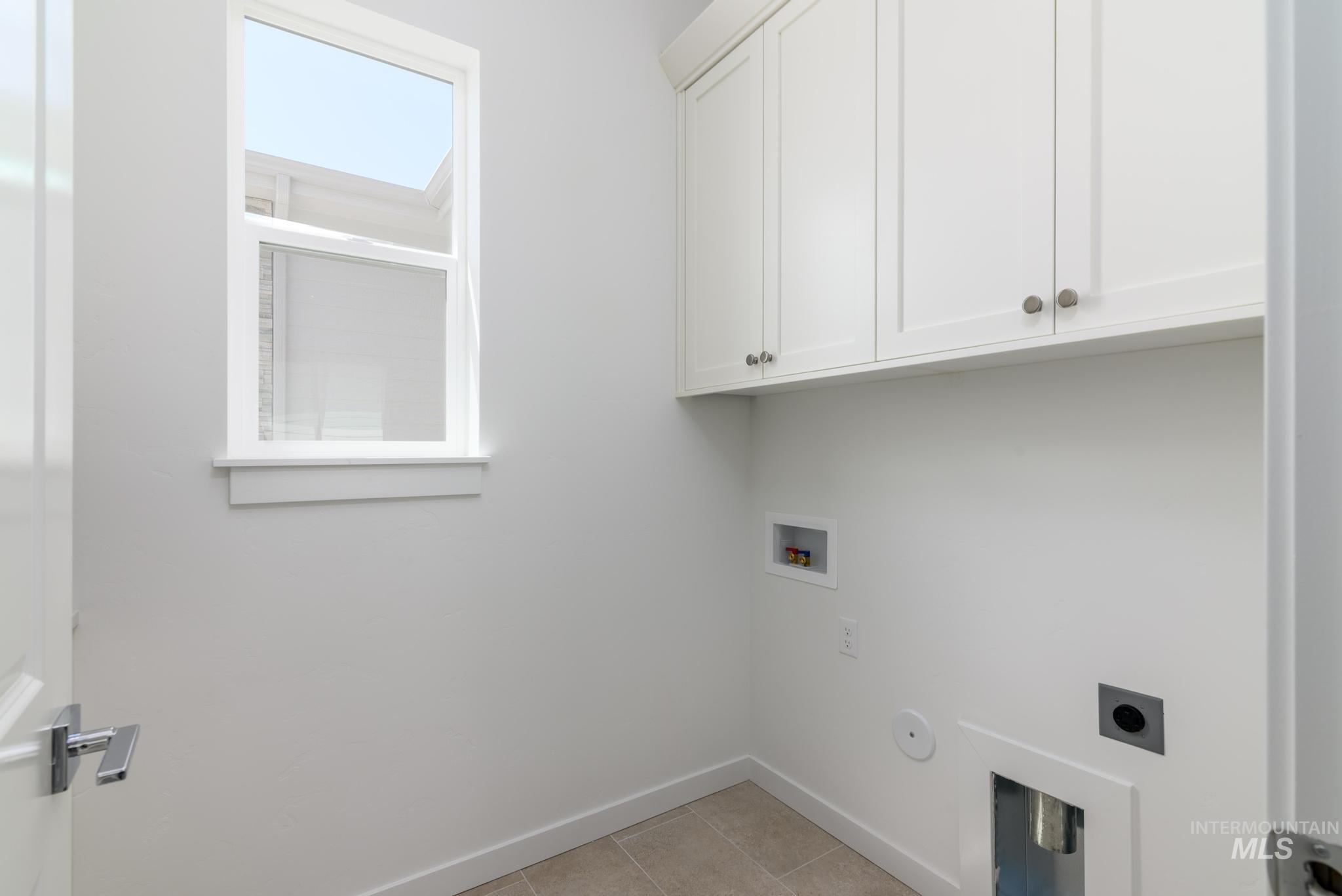 Washroom featuring cabinet space, electric dryer hookup, gas dryer hookup, washer hookup, and light tile patterned floors