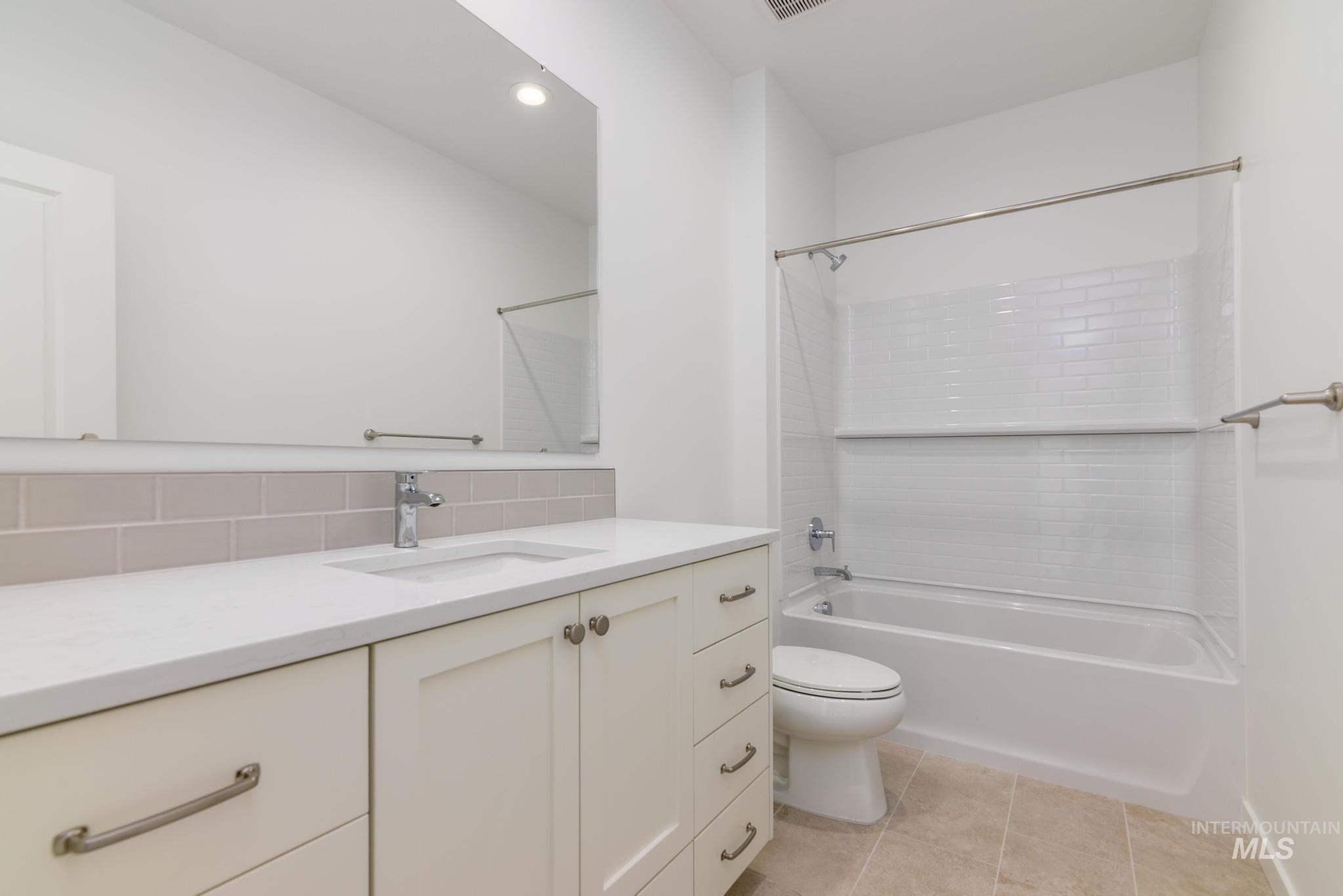 Bathroom with vanity, washtub / shower combination, tasteful backsplash, tile patterned floors, and recessed lighting