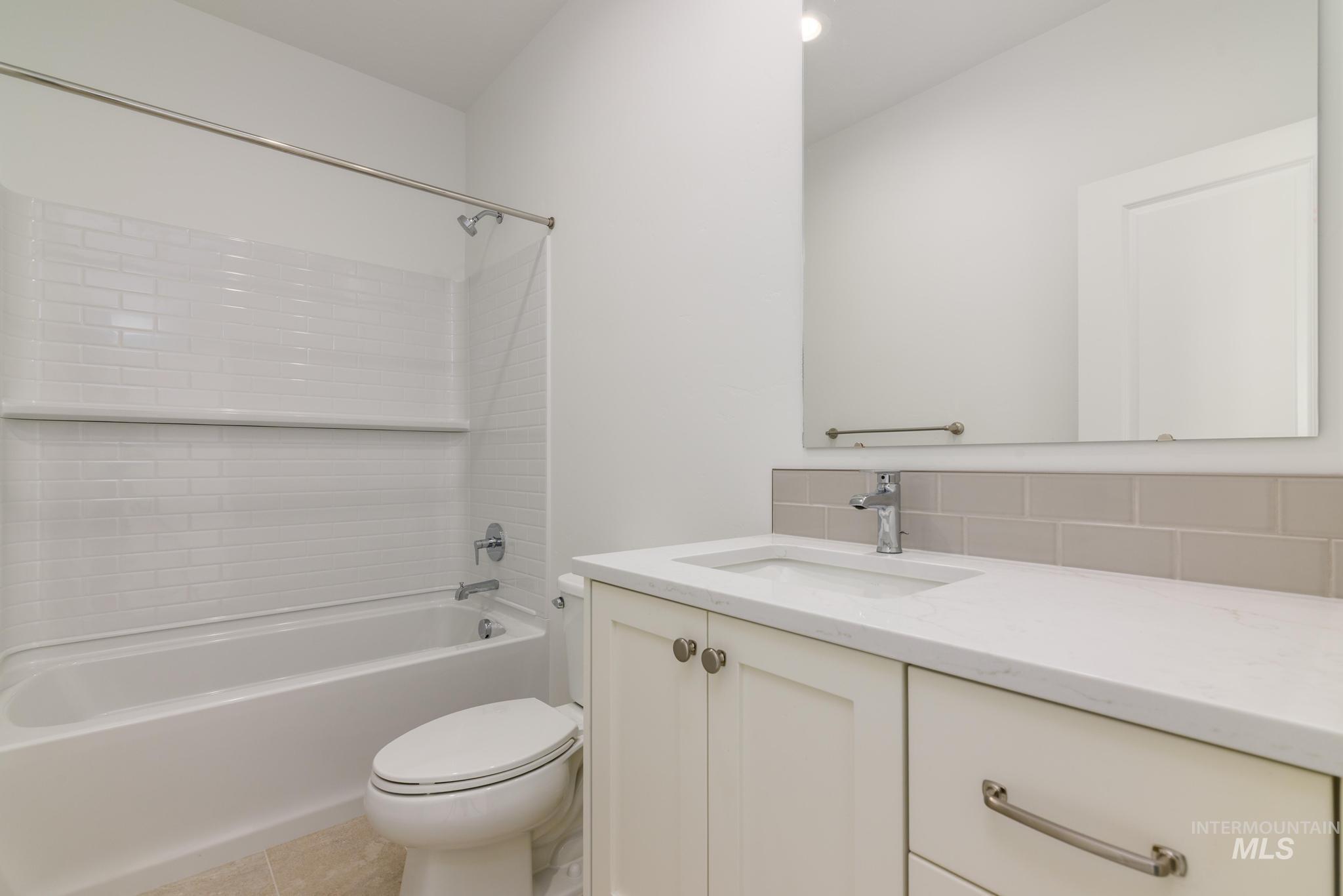 Bathroom featuring vanity, bathtub / shower combination, backsplash, and tile patterned flooring
