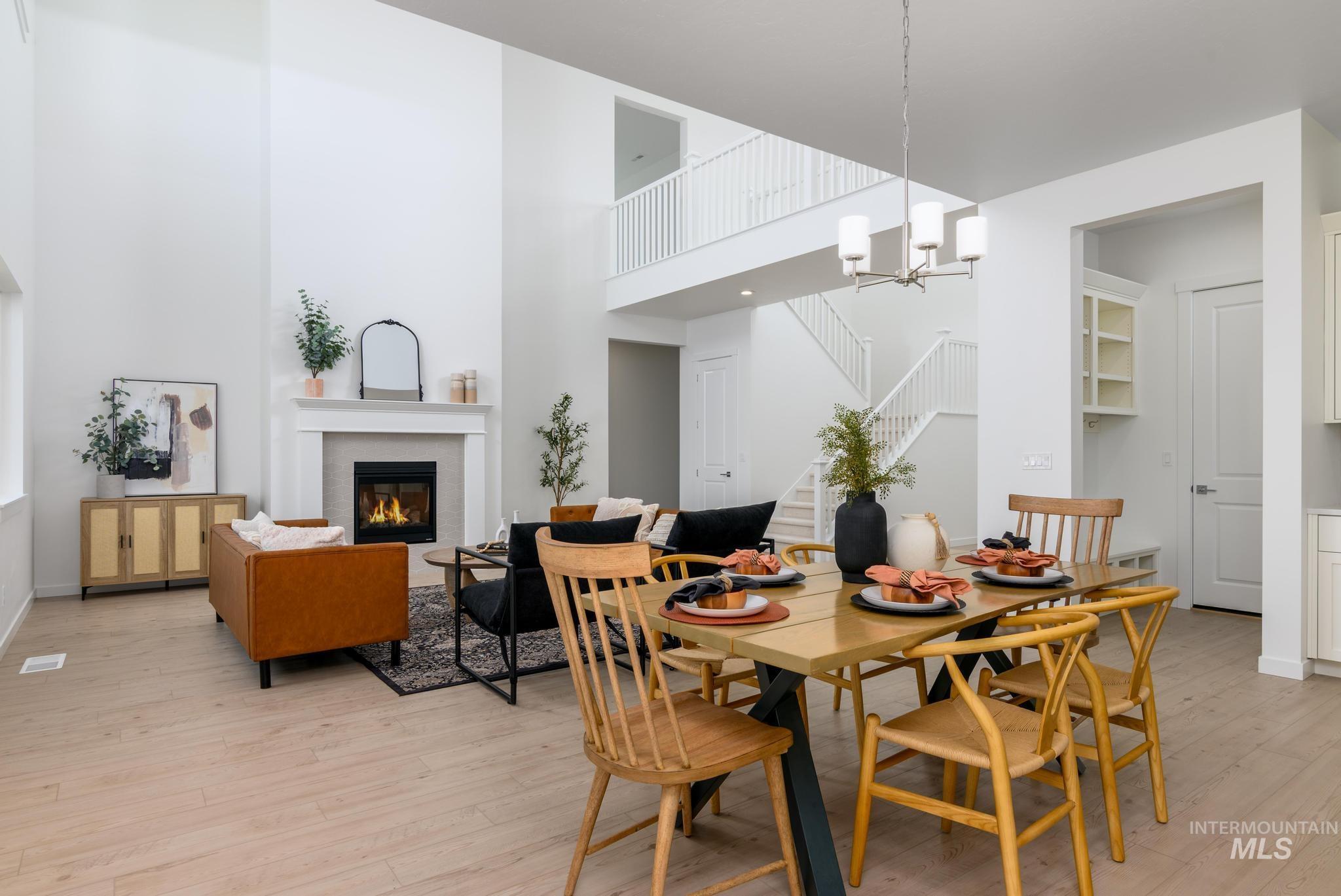 Dining room featuring a glass covered fireplace, a high ceiling, light wood-style flooring, stairway, and a chandelier