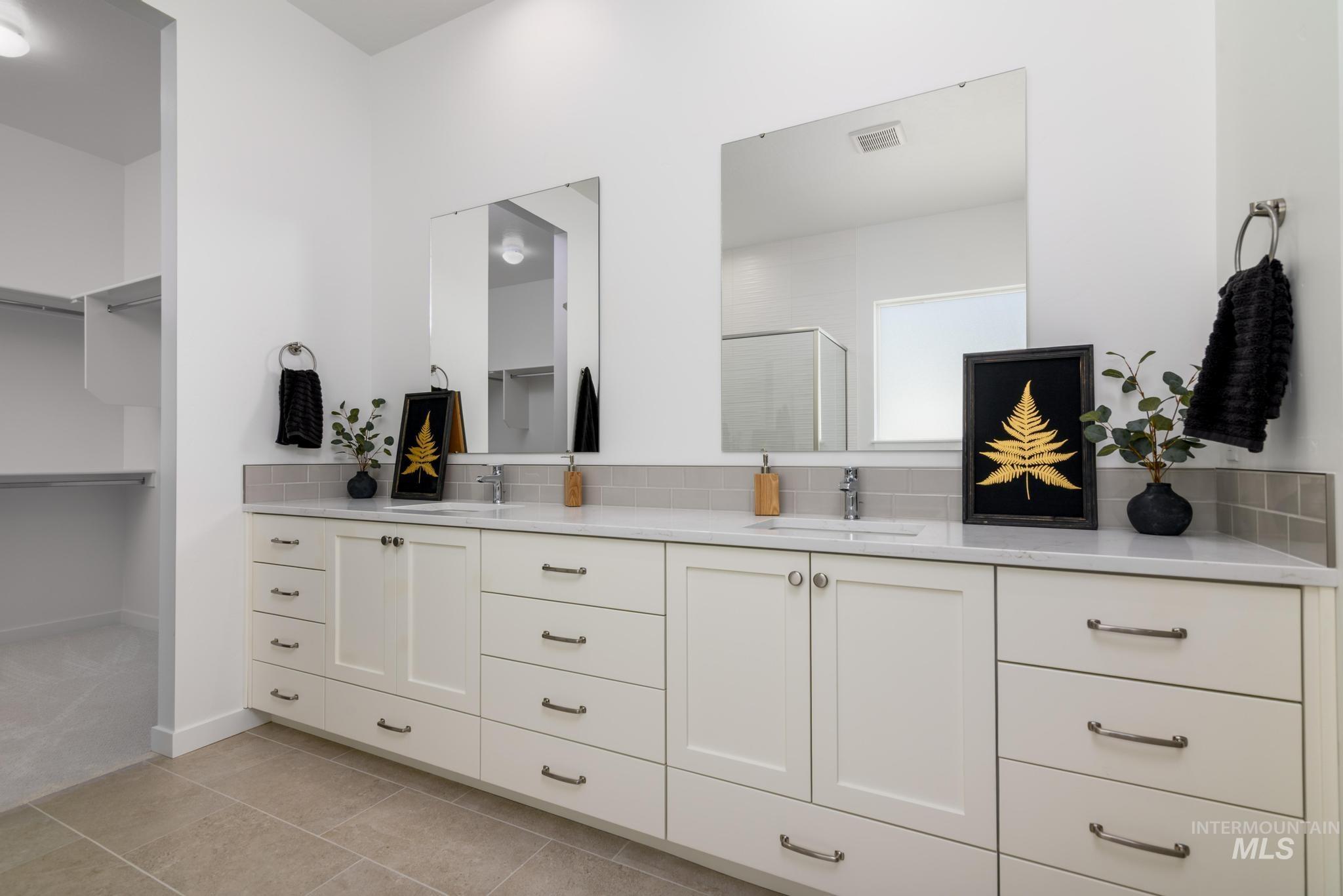 Full bathroom with double vanity, a shower stall, a walk in closet, and tile patterned floors