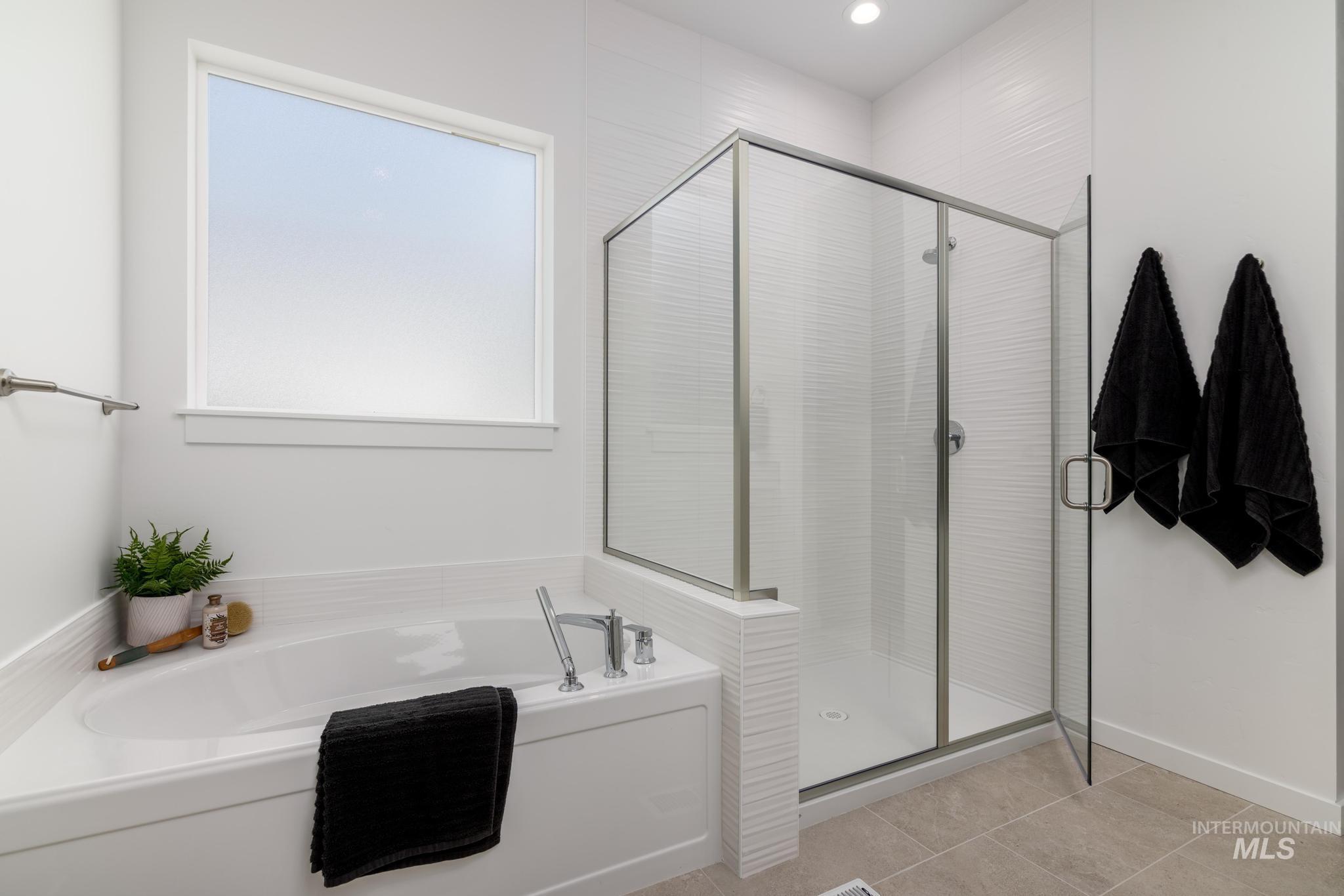 Bathroom with a garden tub, a shower stall, and tile patterned floors