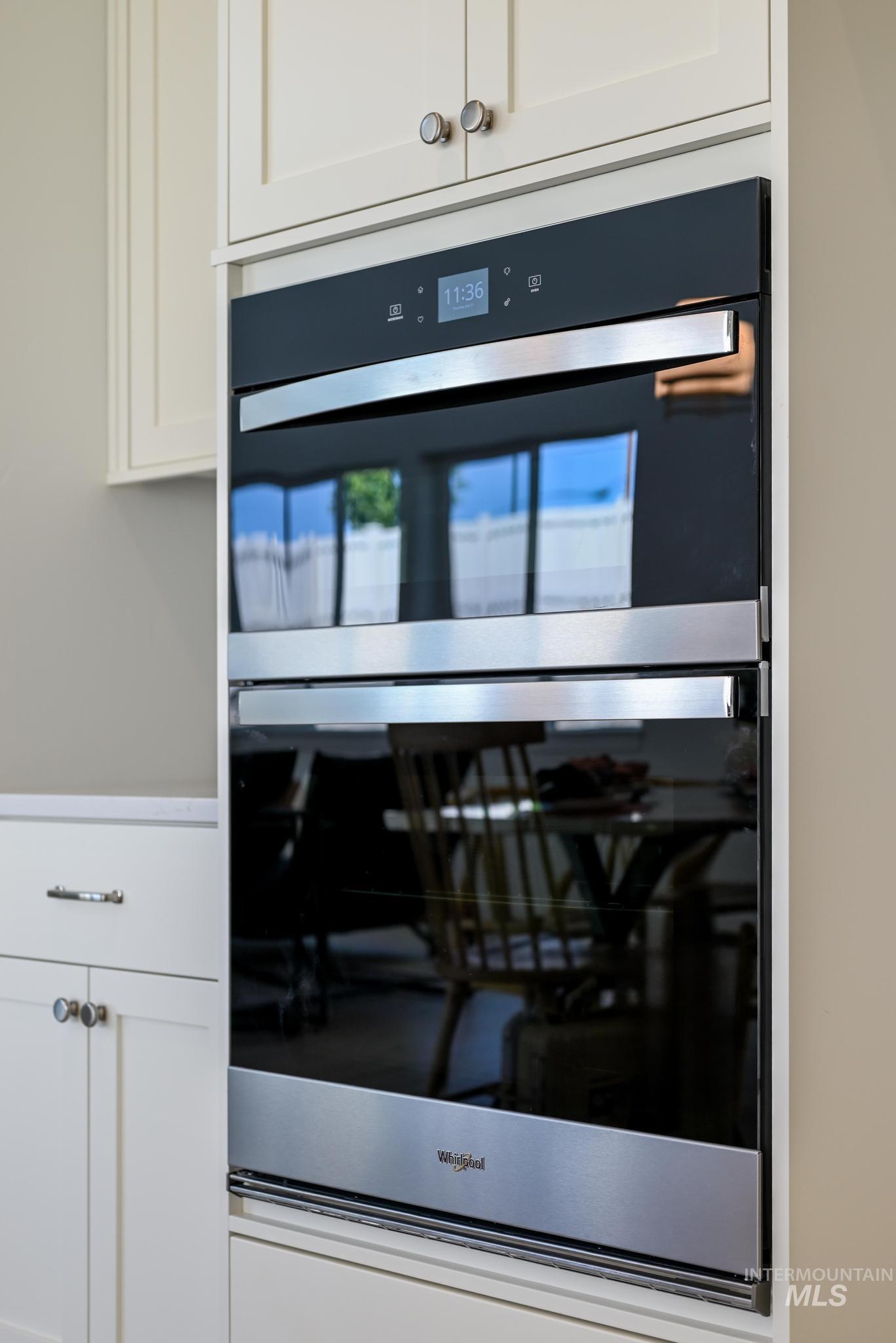 Kitchen view of stainless steel double oven and white cabinets