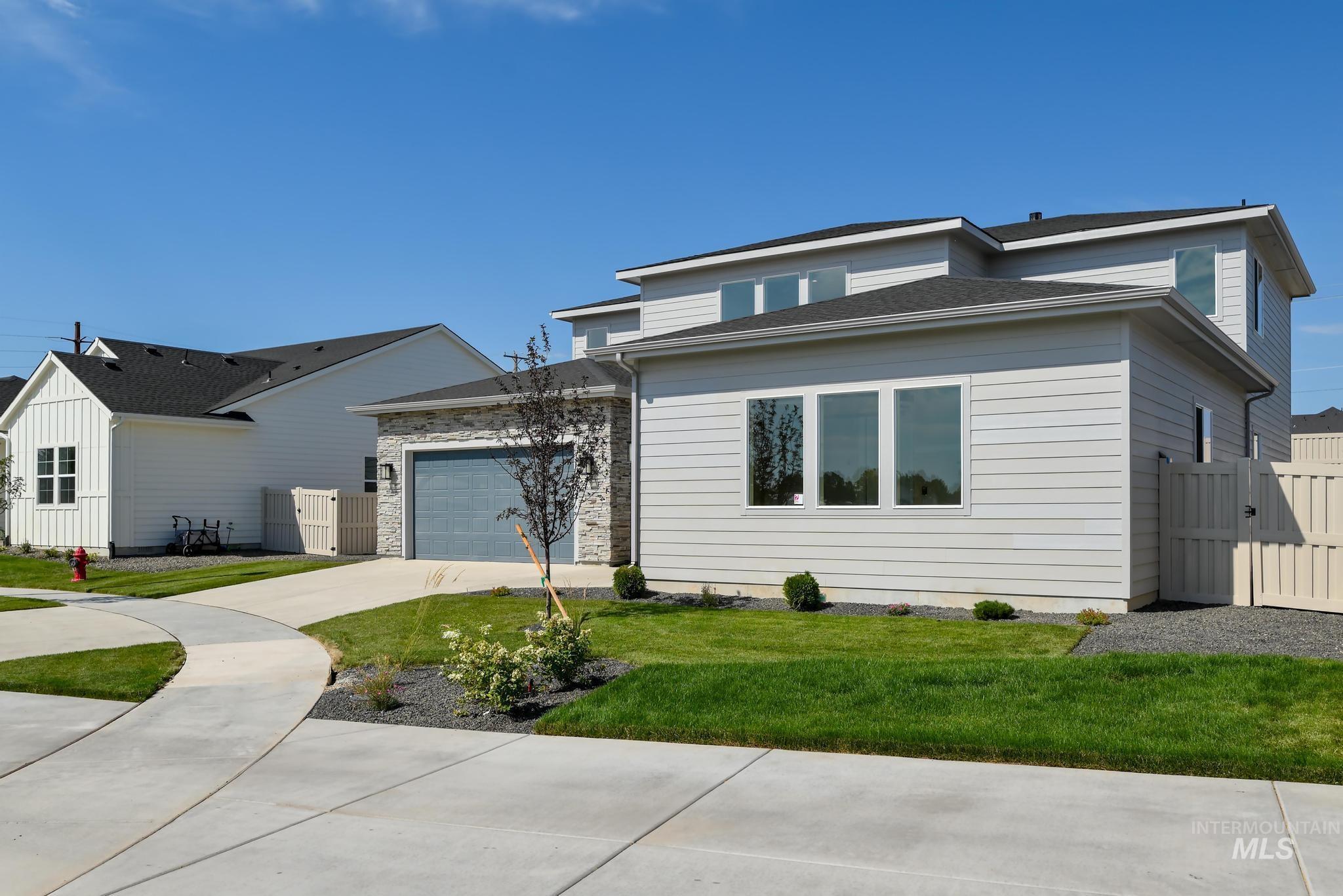 View of front facade featuring driveway, a garage, a gate, and stone siding
