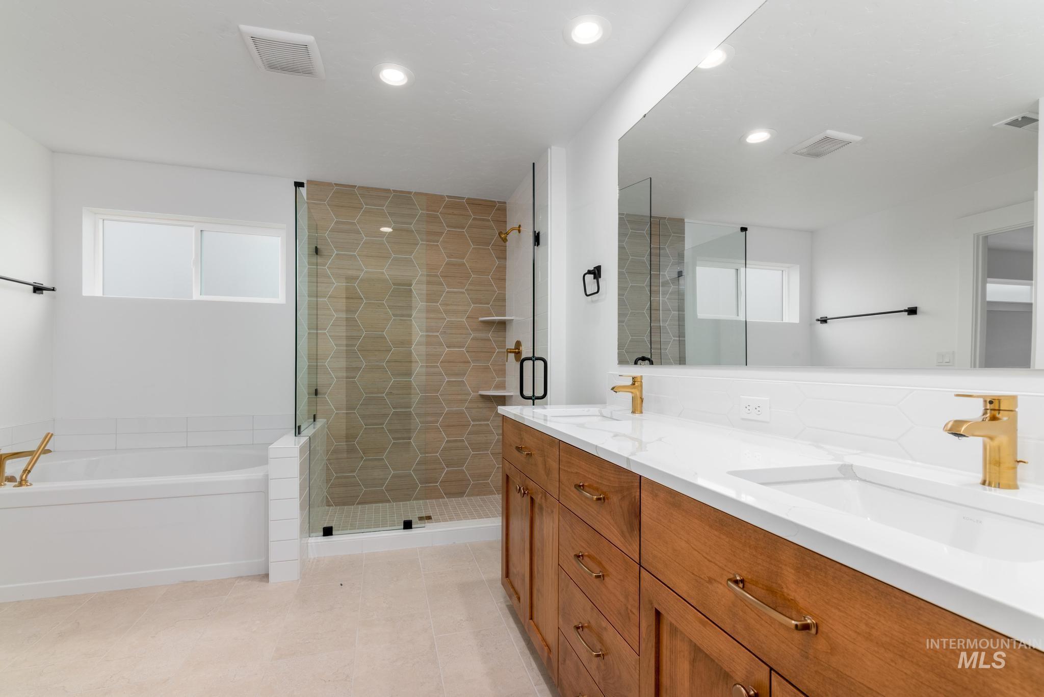 Bathroom featuring a bath, double vanity, a stall shower, recessed lighting, and light tile patterned flooring