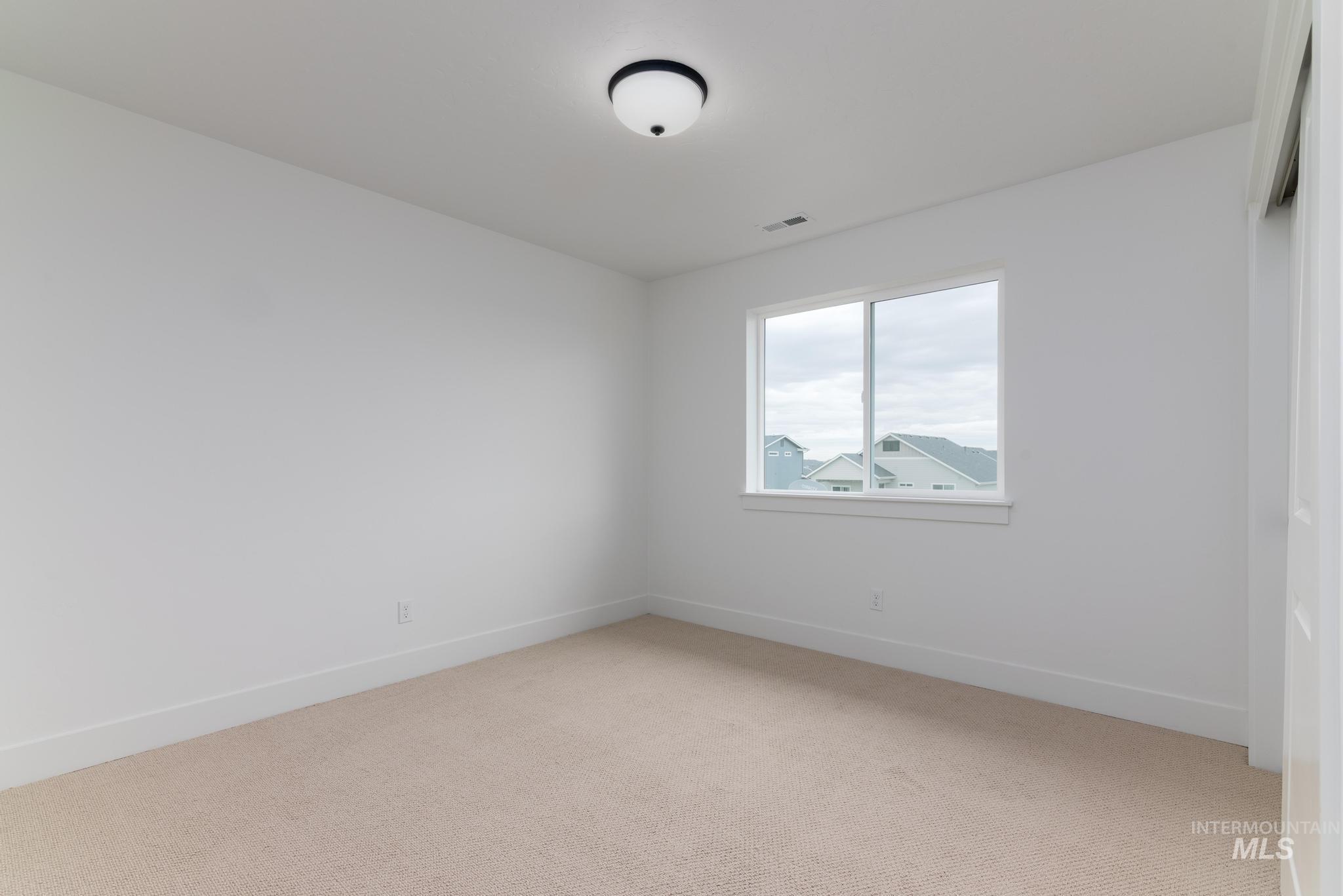Spare room with light carpet and baseboards