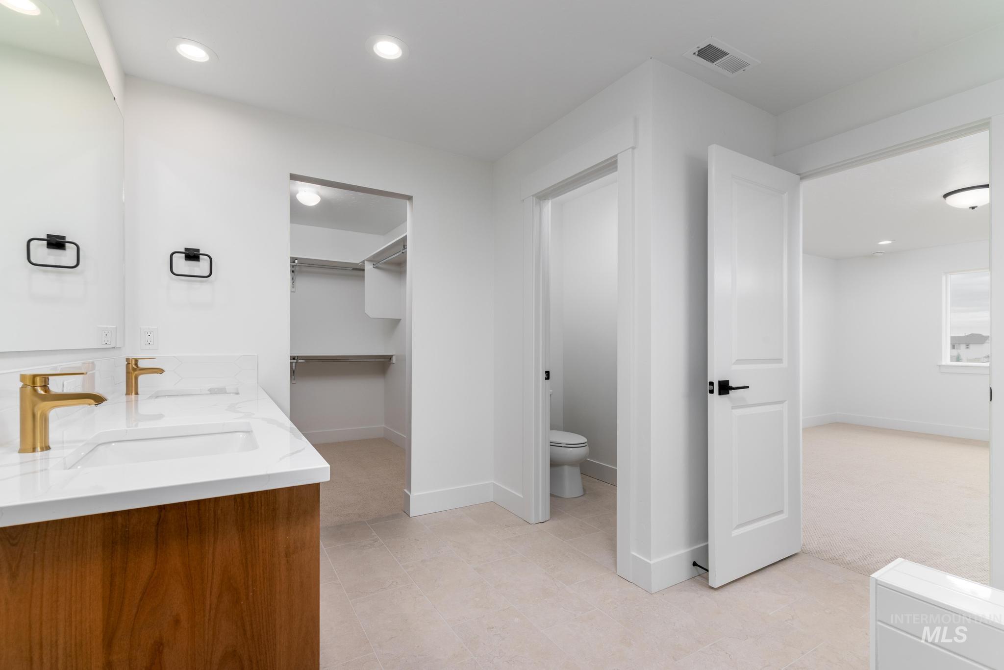 Full bathroom with double vanity, recessed lighting, and a spacious closet