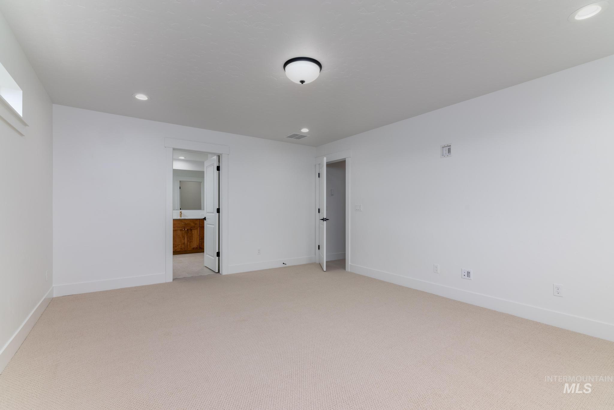 Unfurnished bedroom with recessed lighting, light carpet, and ensuite bath