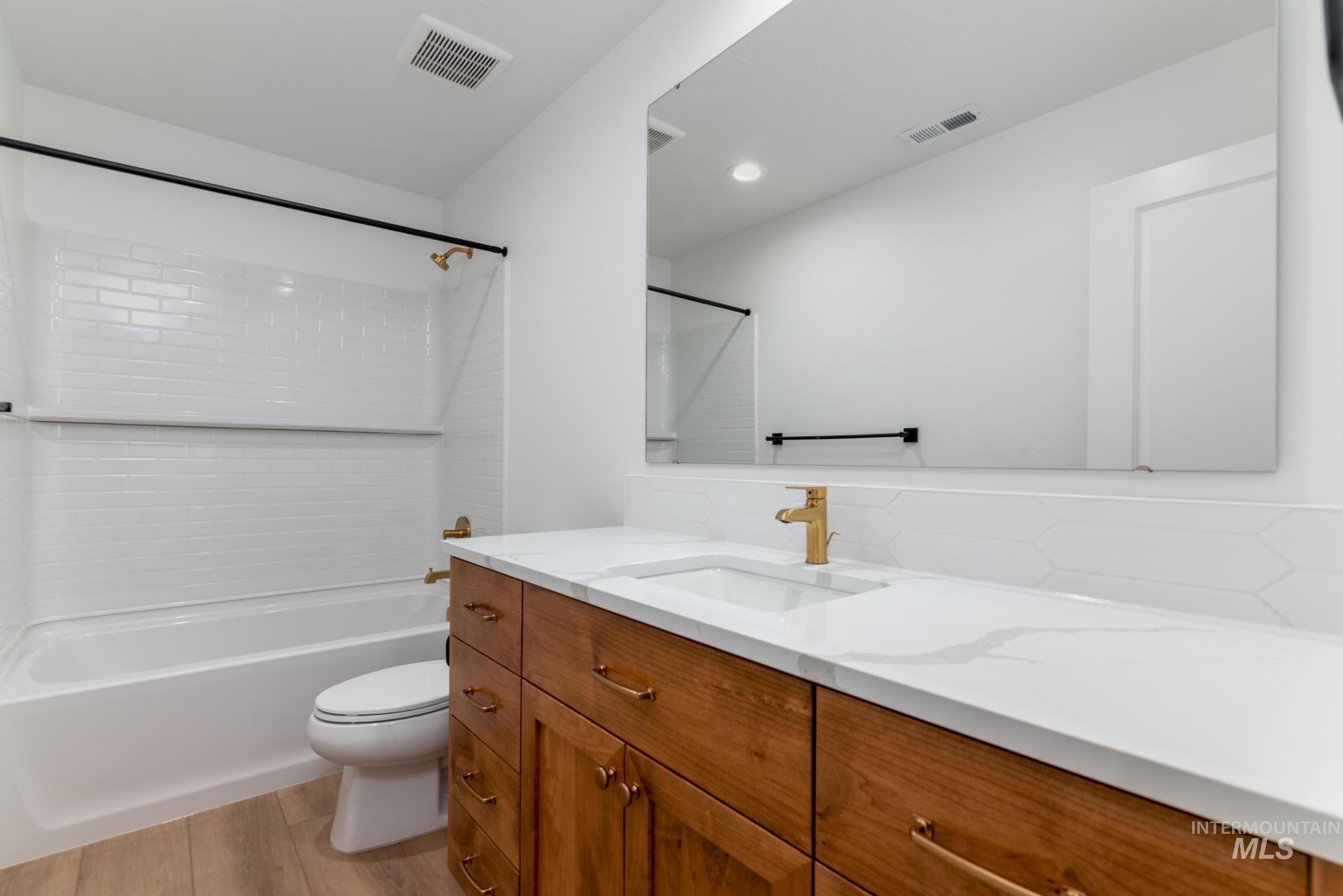 Bathroom with vanity, light wood-type flooring, bathing tub / shower combination, tasteful backsplash, and recessed lighting
