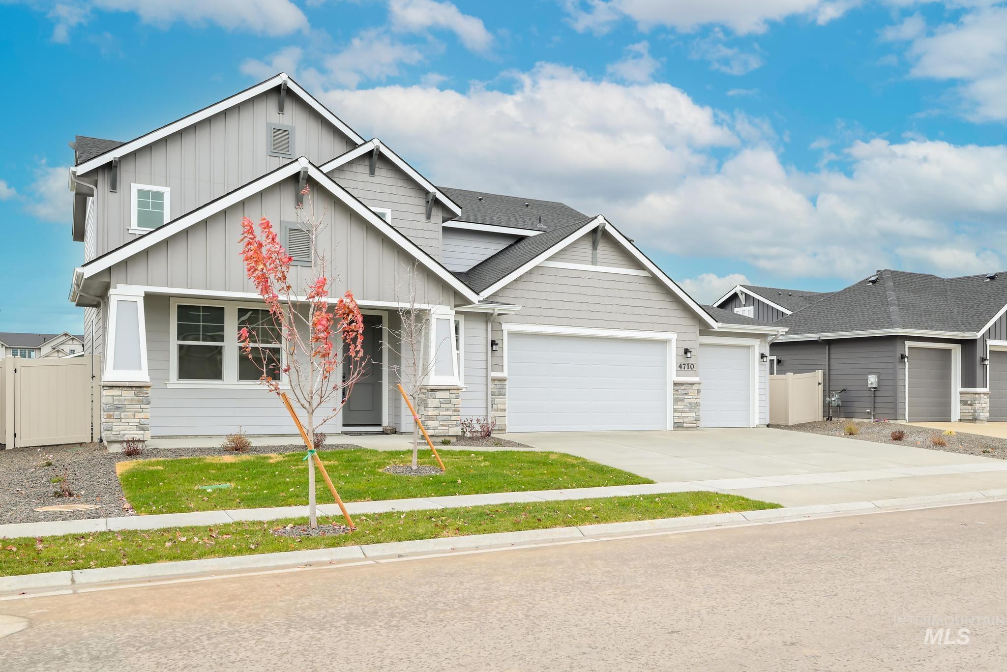Craftsman house featuring board and batten siding, driveway, an attached garage, stone siding, and a gate