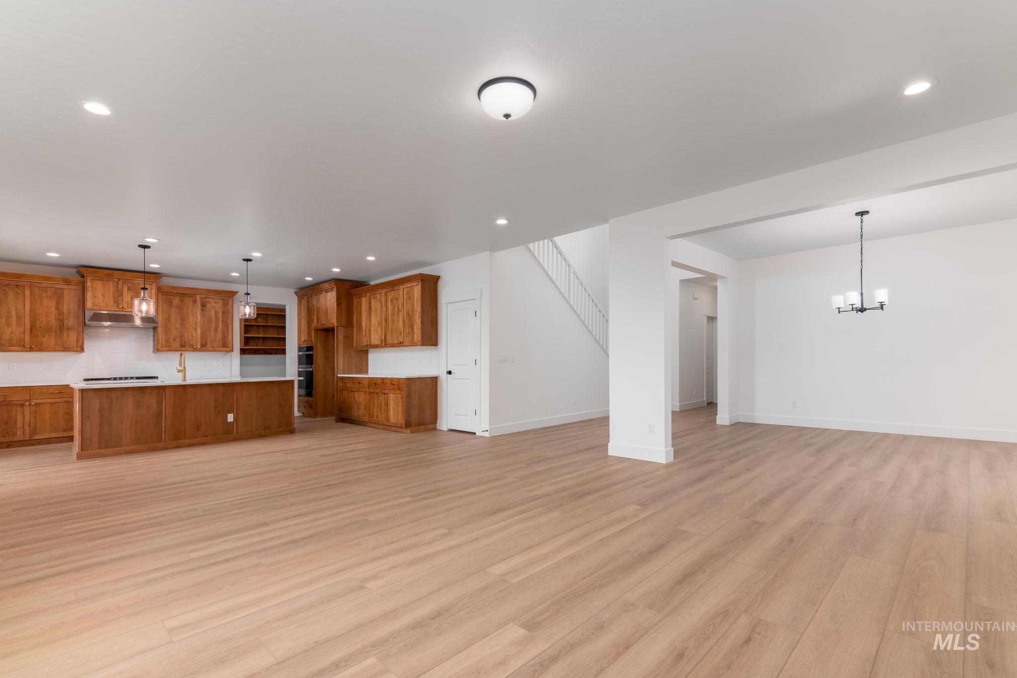 Unfurnished living room featuring light wood-style flooring, recessed lighting, and a chandelier