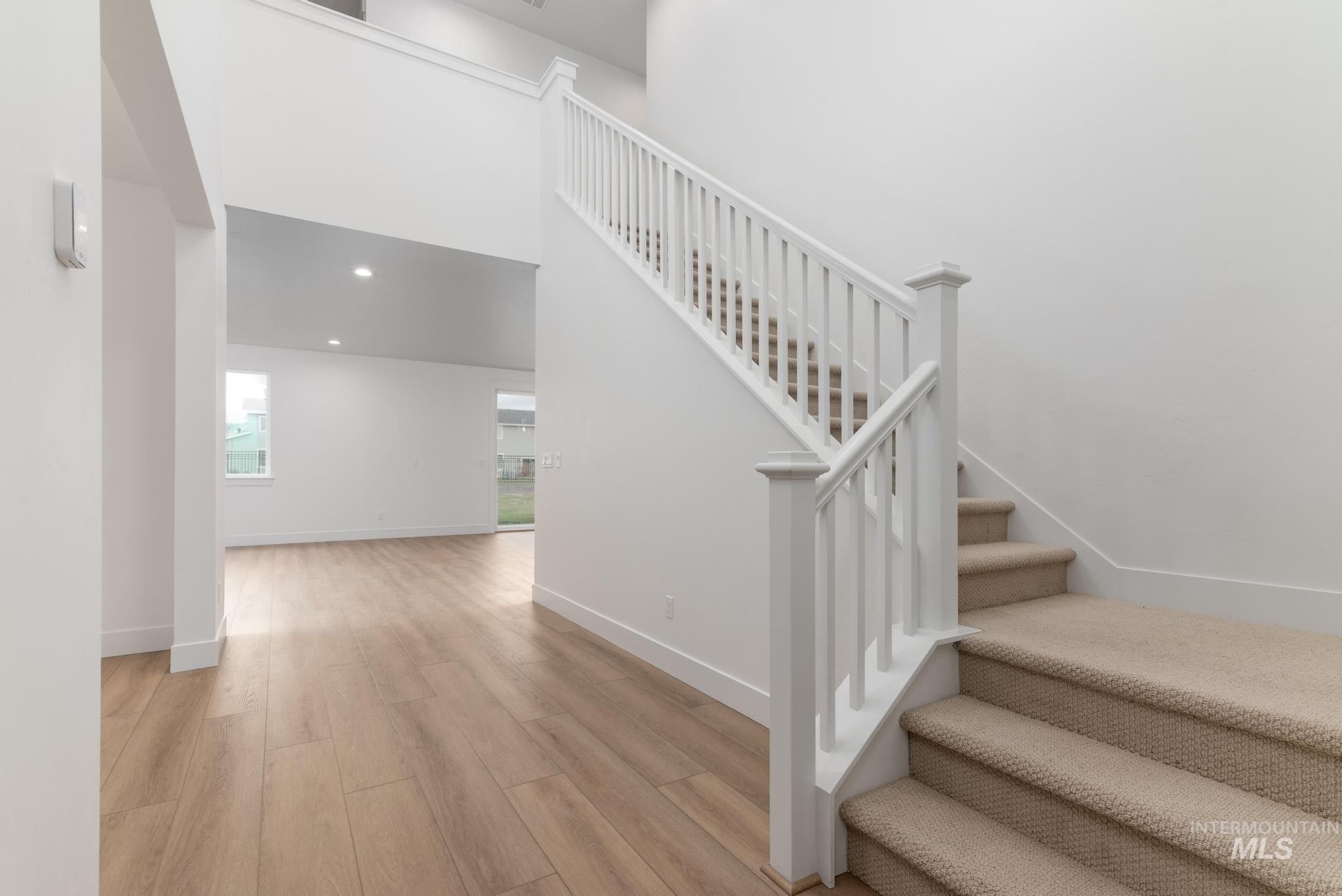 Stairs with a high ceiling, wood finished floors, and recessed lighting