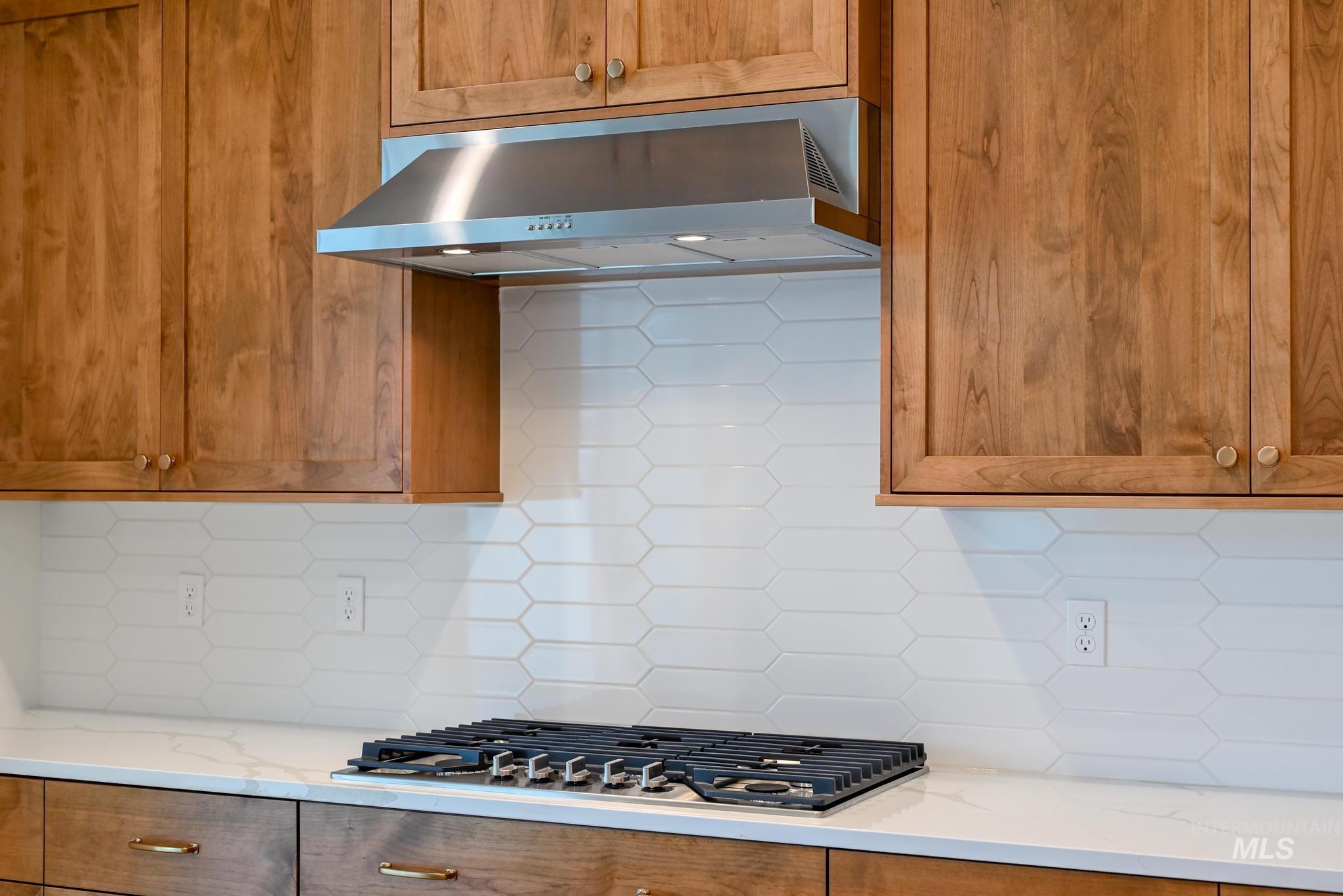 Kitchen with decorative backsplash, light stone counters, and brown cabinets