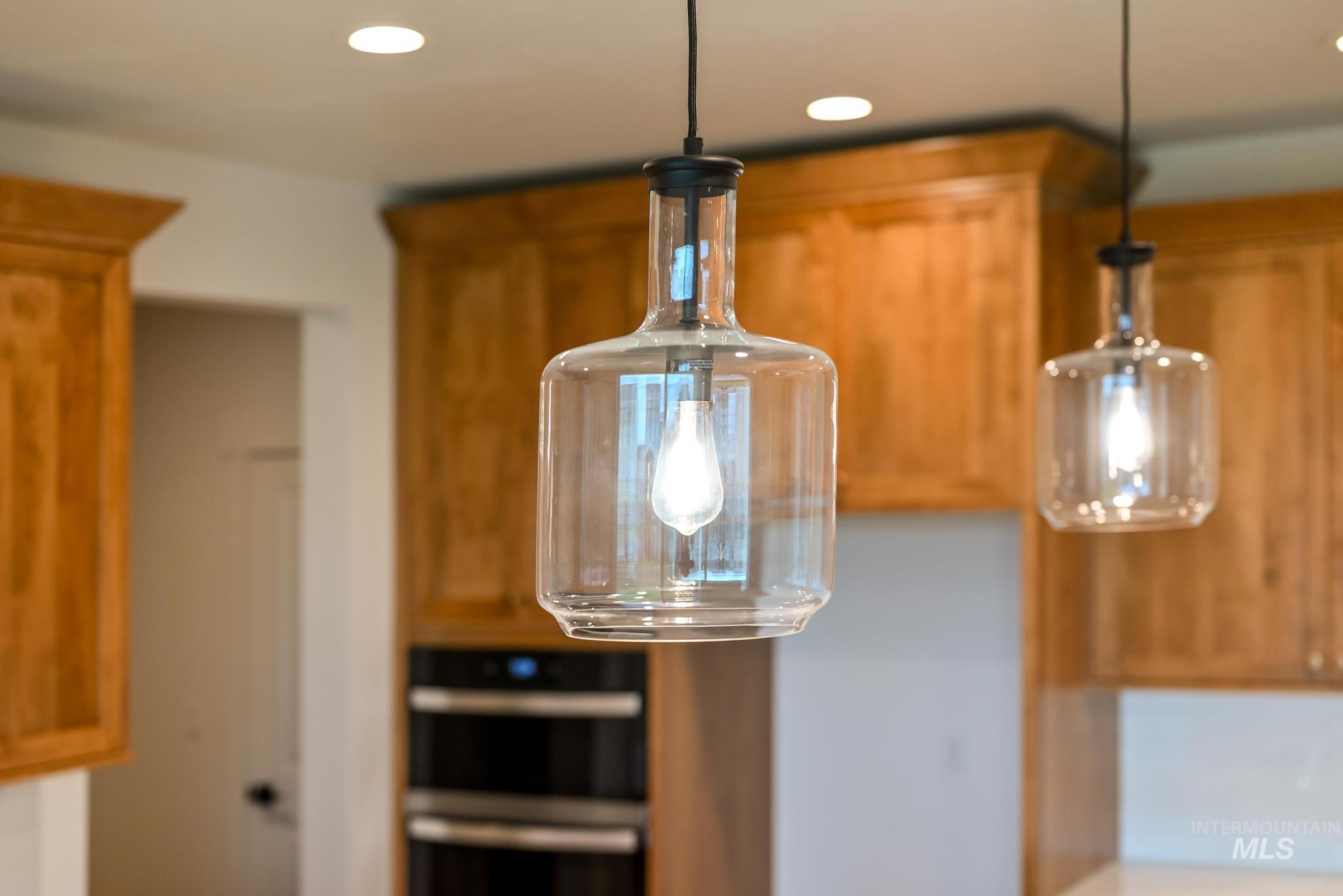 Kitchen view of brown cabinets, recessed lighting, pendant lighting, and stainless steel double oven