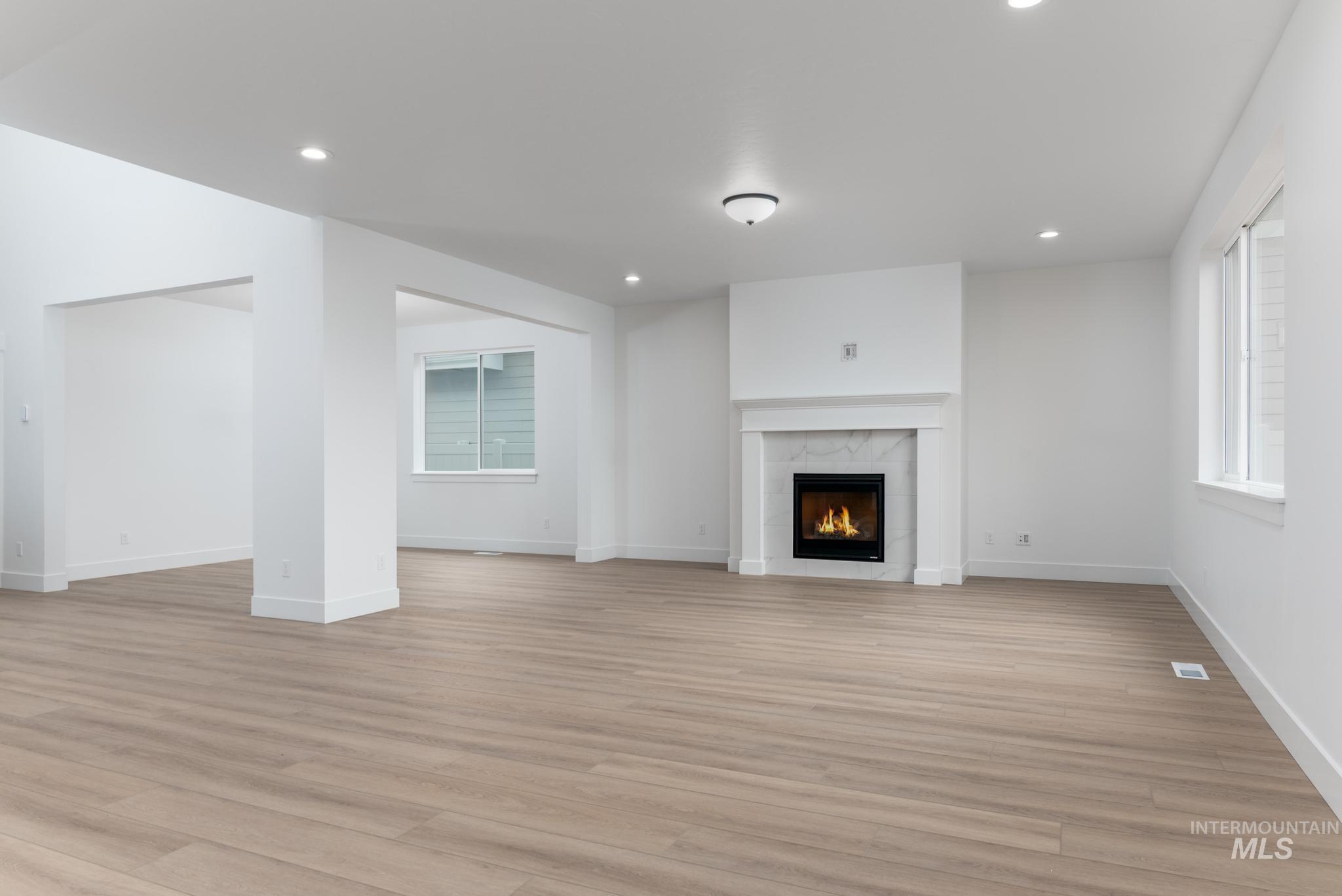 Unfurnished living room featuring light wood-style flooring, a tile fireplace, and recessed lighting