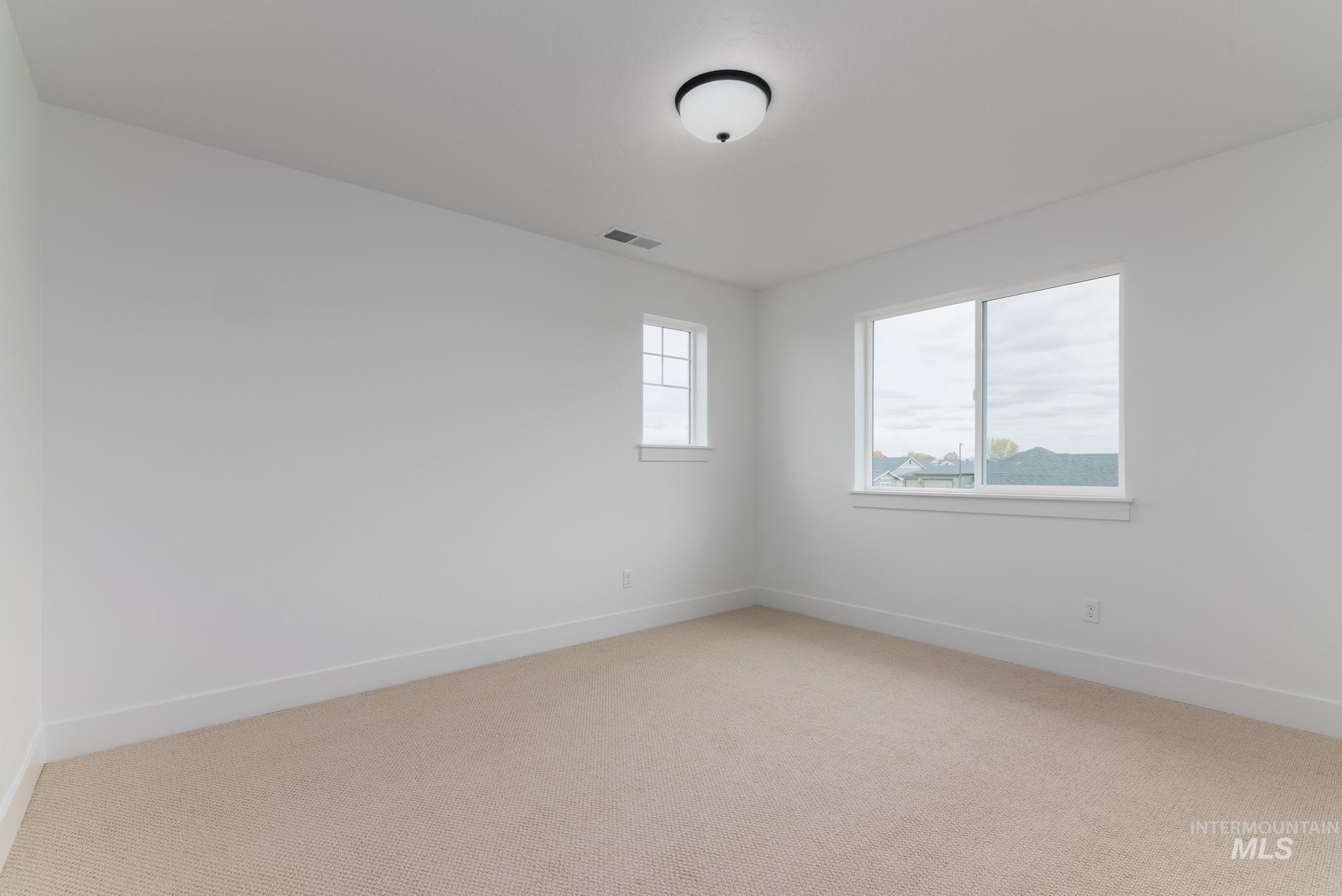 Spare room featuring light colored carpet and baseboards