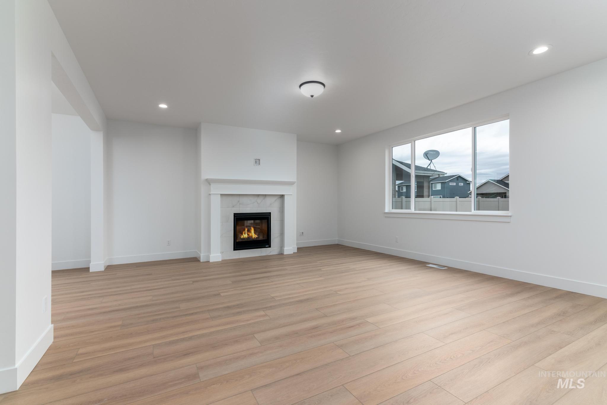 Unfurnished living room with light wood-type flooring, a tiled fireplace, and recessed lighting