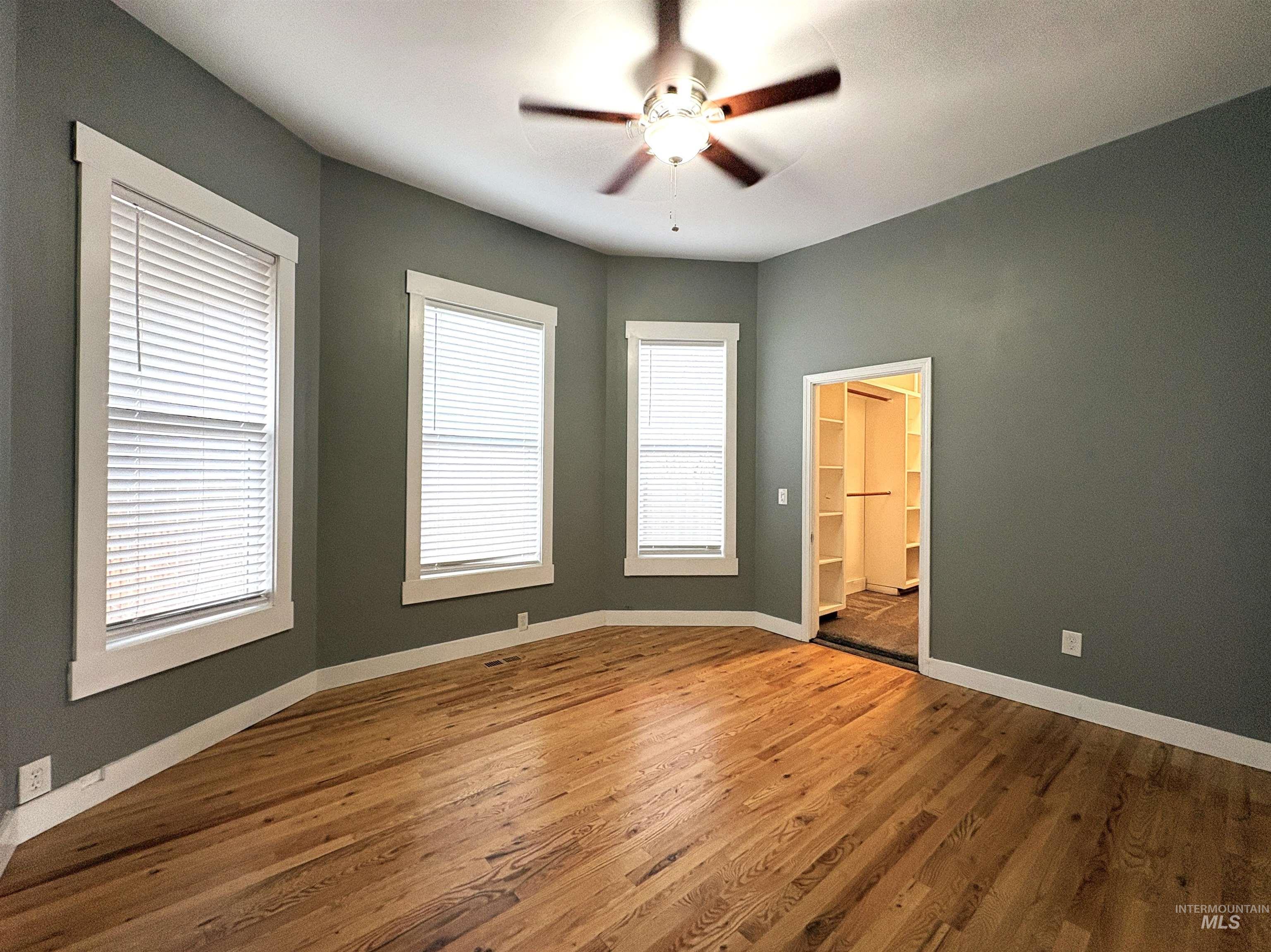 Large main level master bedroom with walk in closet and wood flooring.
