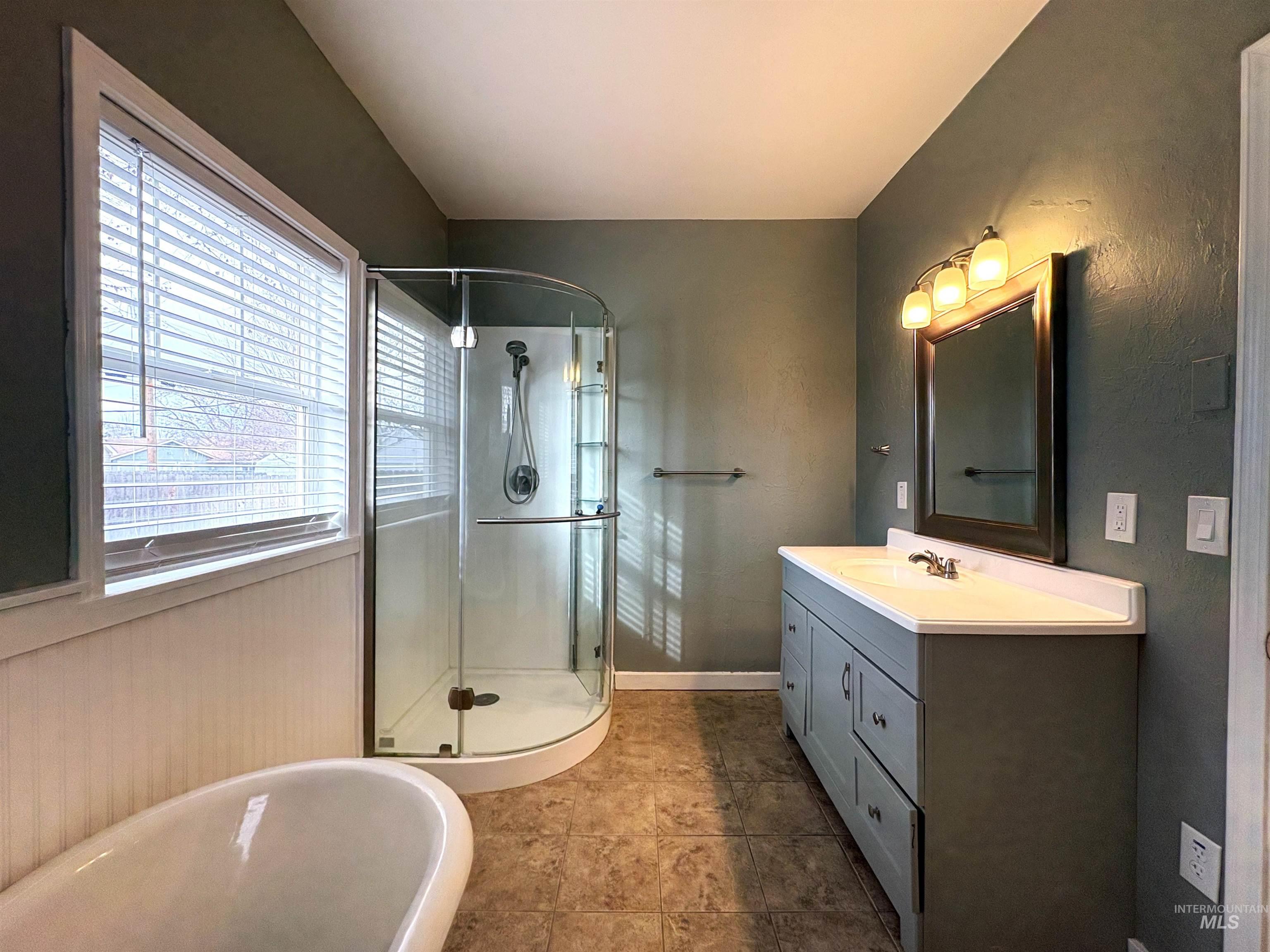 Bathroom with vanity, a shower stall, and tile patterned flooring