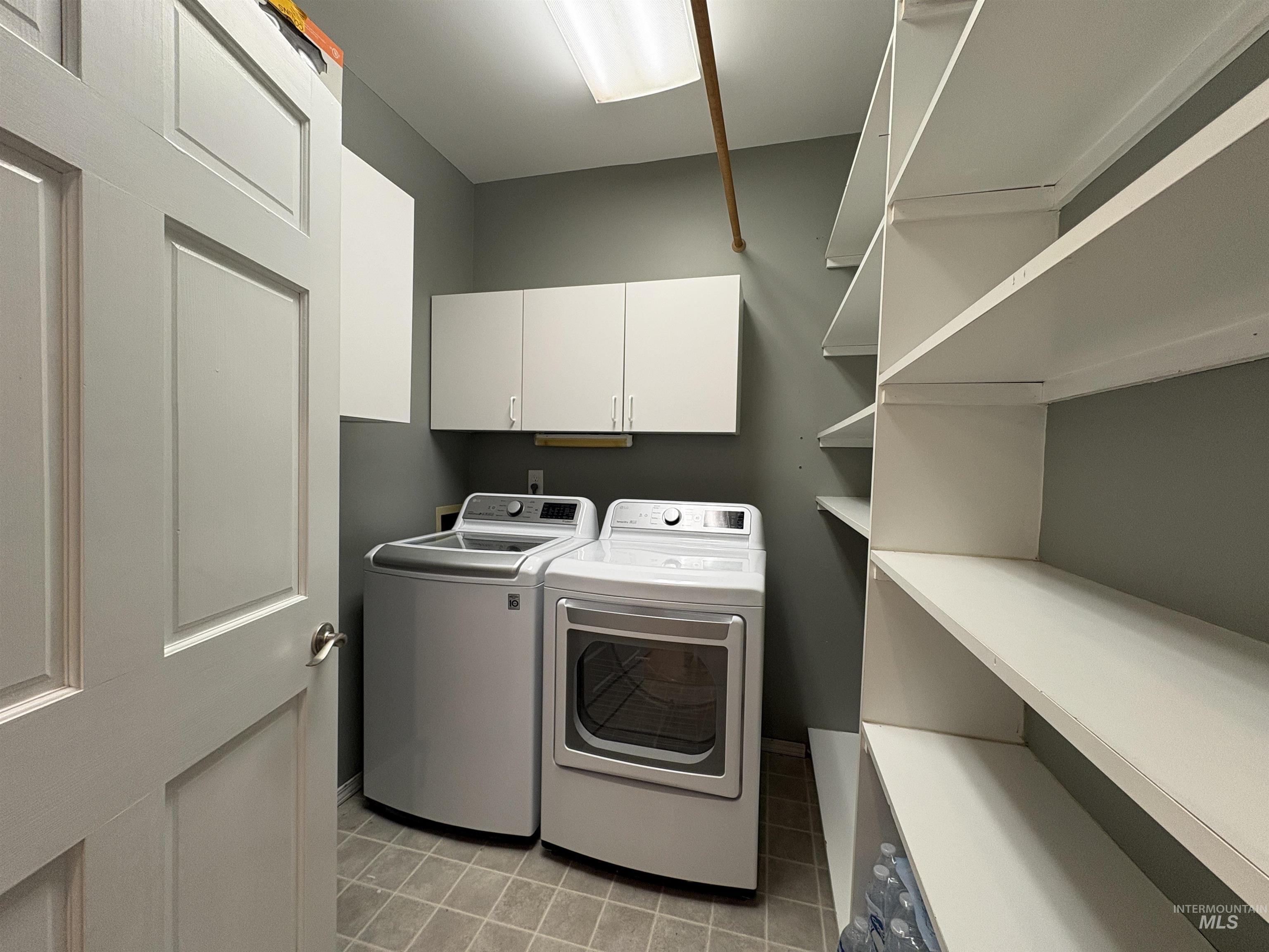 Laundry room with washer and dryer, cabinet space, and open pantry shelving.