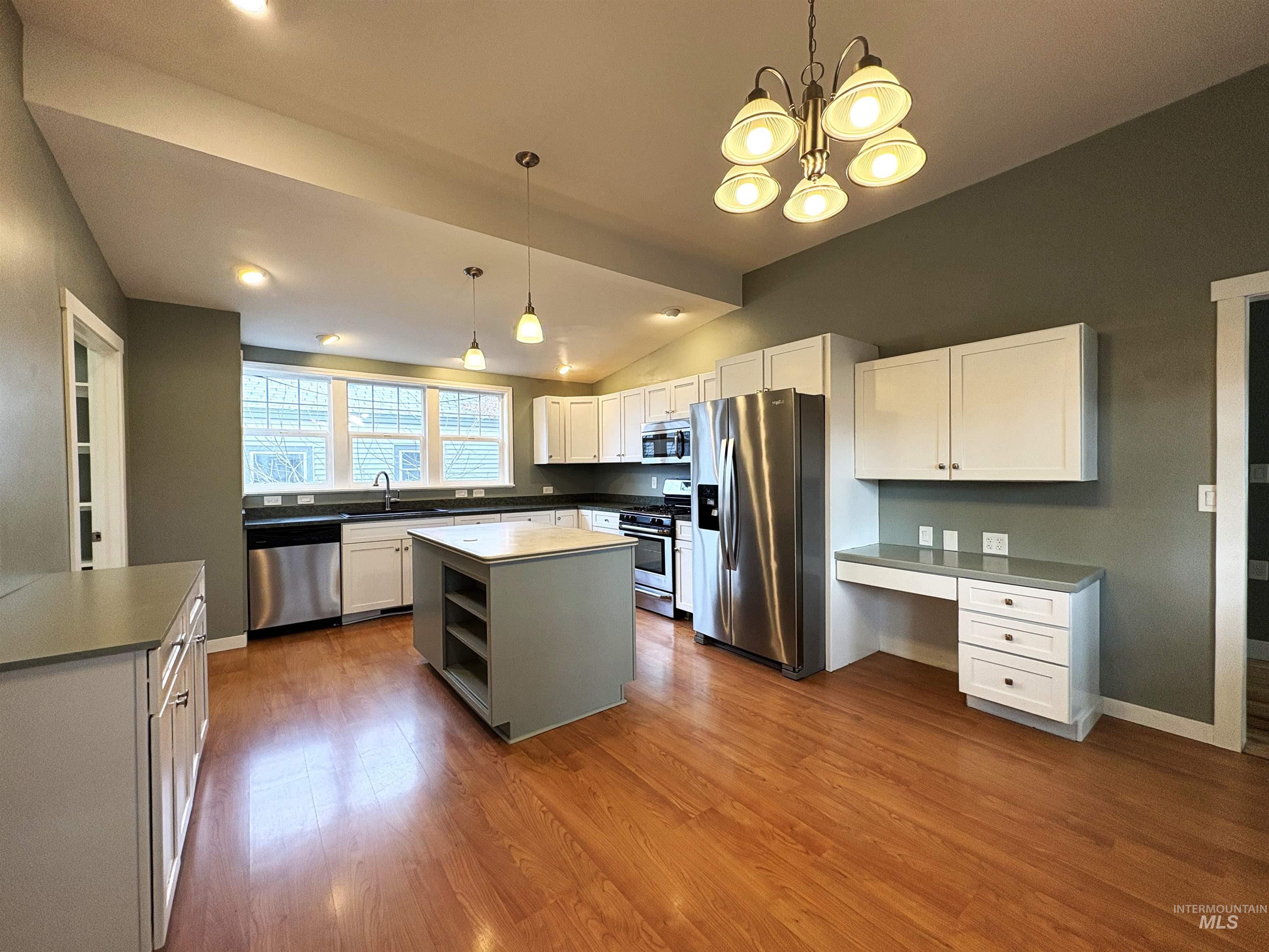 Kitchen featuring stainless steel appliances, open shelves, white cabinetry, vaulted ceiling, and dark wood