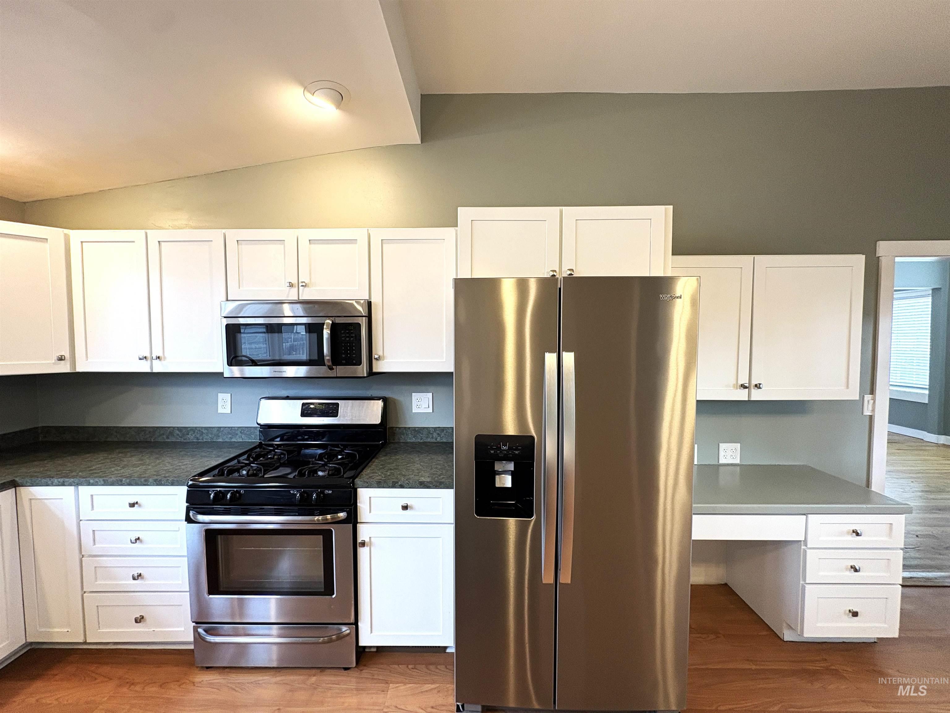 Kitchen featuring stainless steel appliances, dark wood-style floors, and white cabinetry