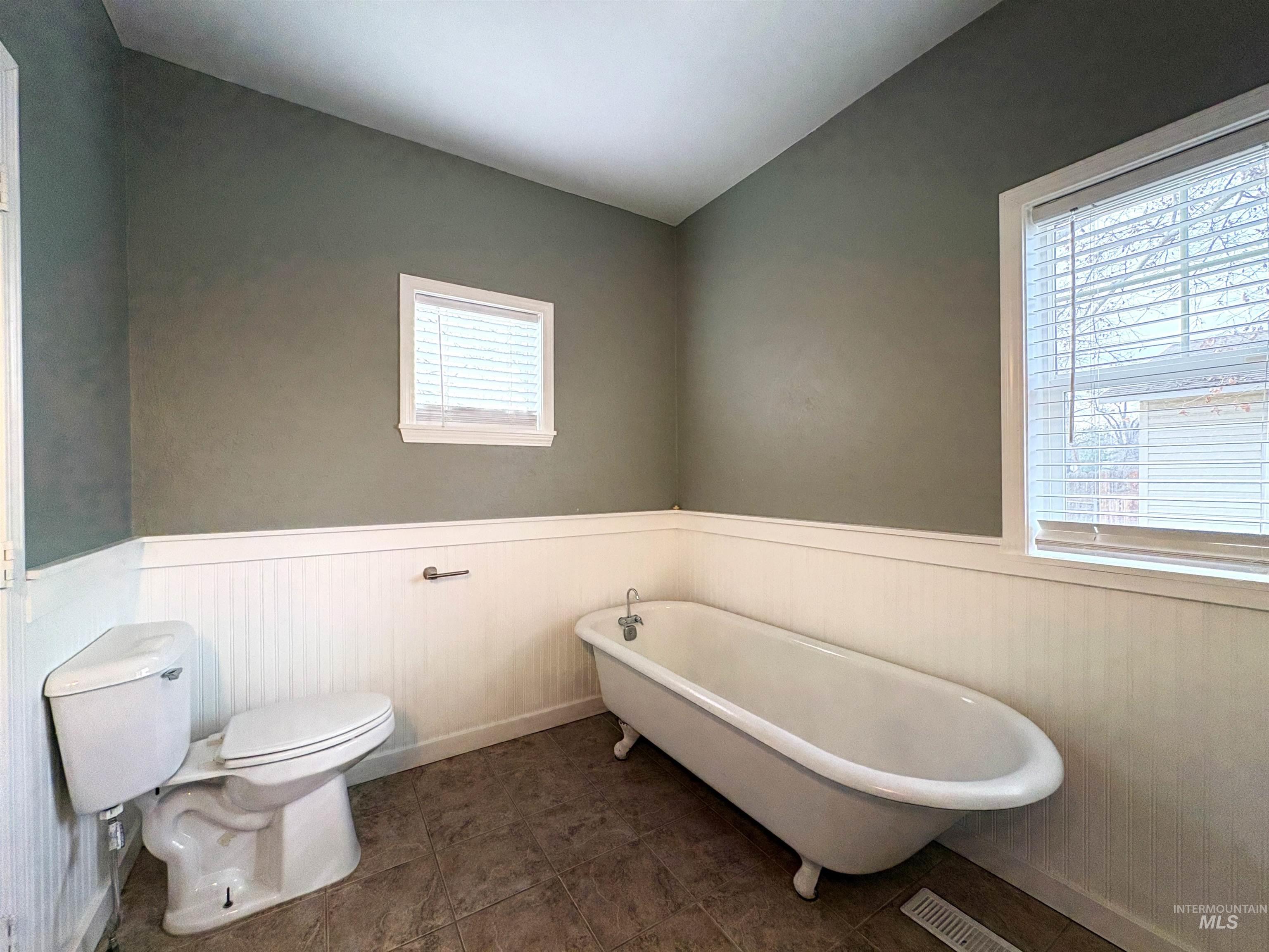 Full bath with a freestanding tub and a wainscoted wall