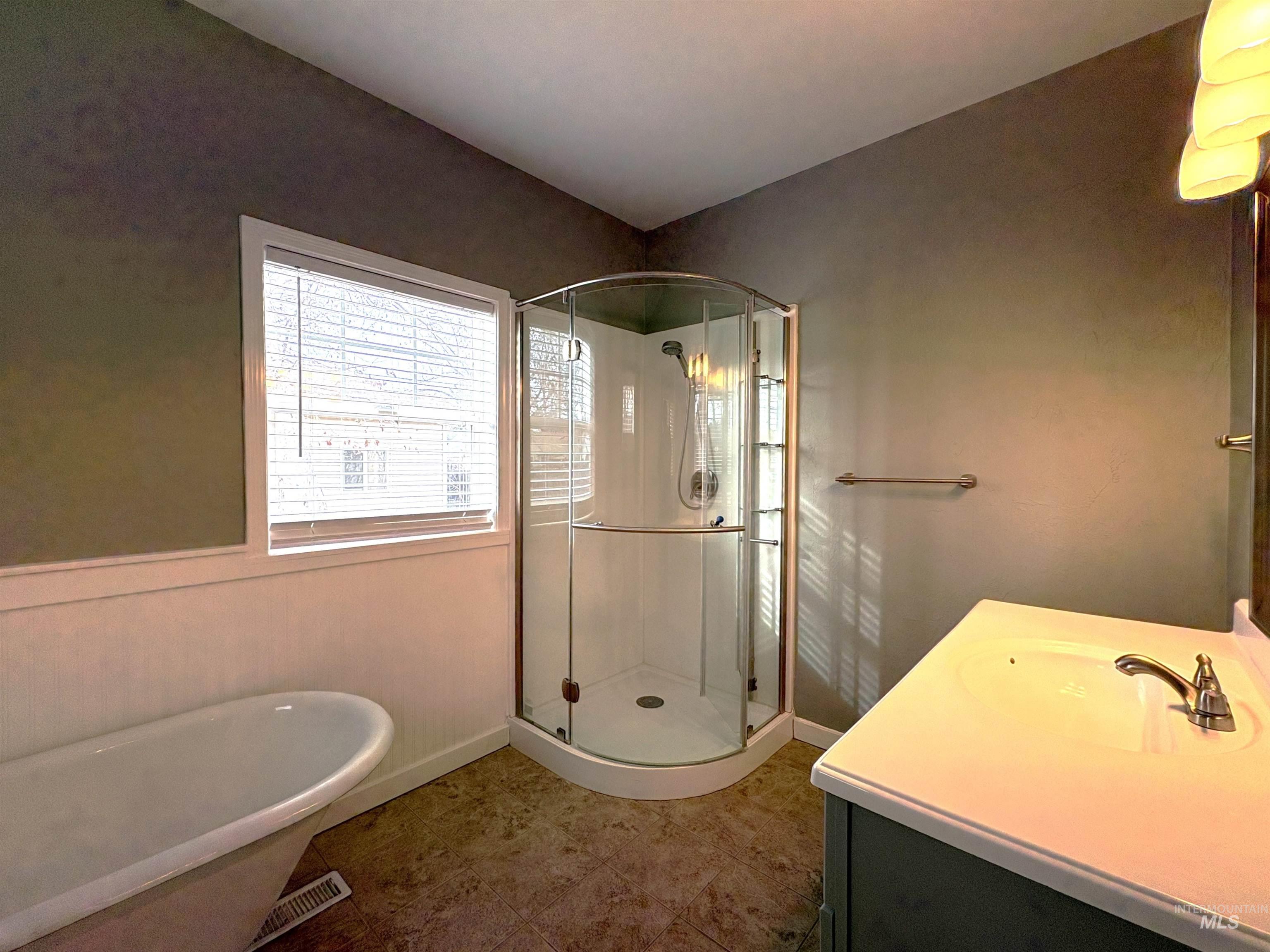 Full bathroom featuring a stall shower, vanity, and a freestanding tub