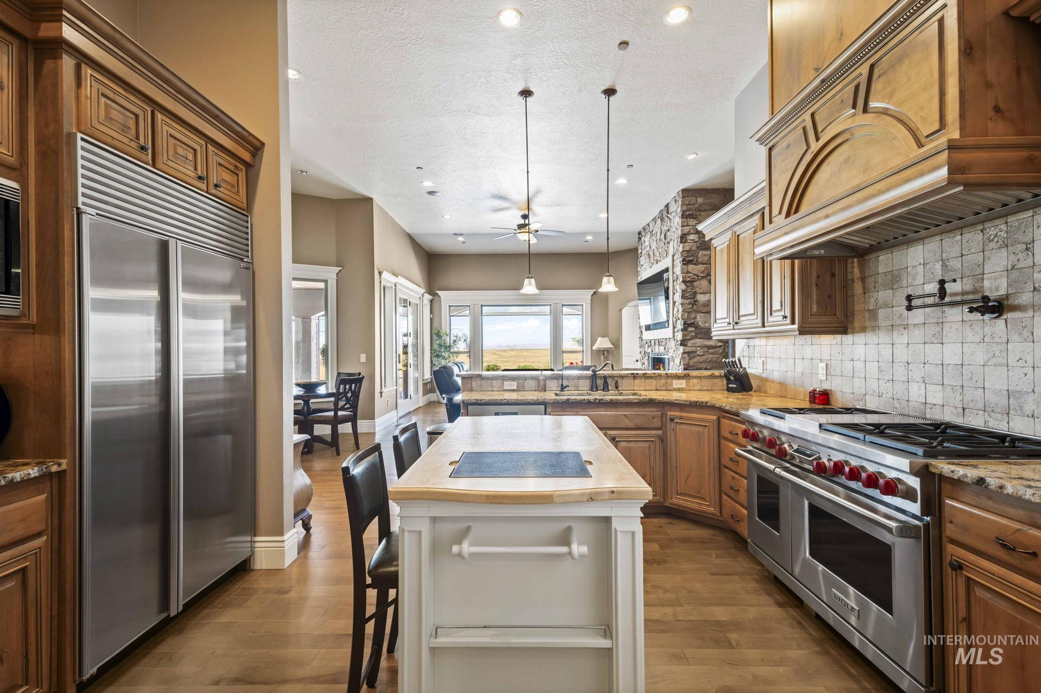 Kitchen featuring high quality appliances, decorative backsplash, custom exhaust hood, a peninsula, and recessed lighting