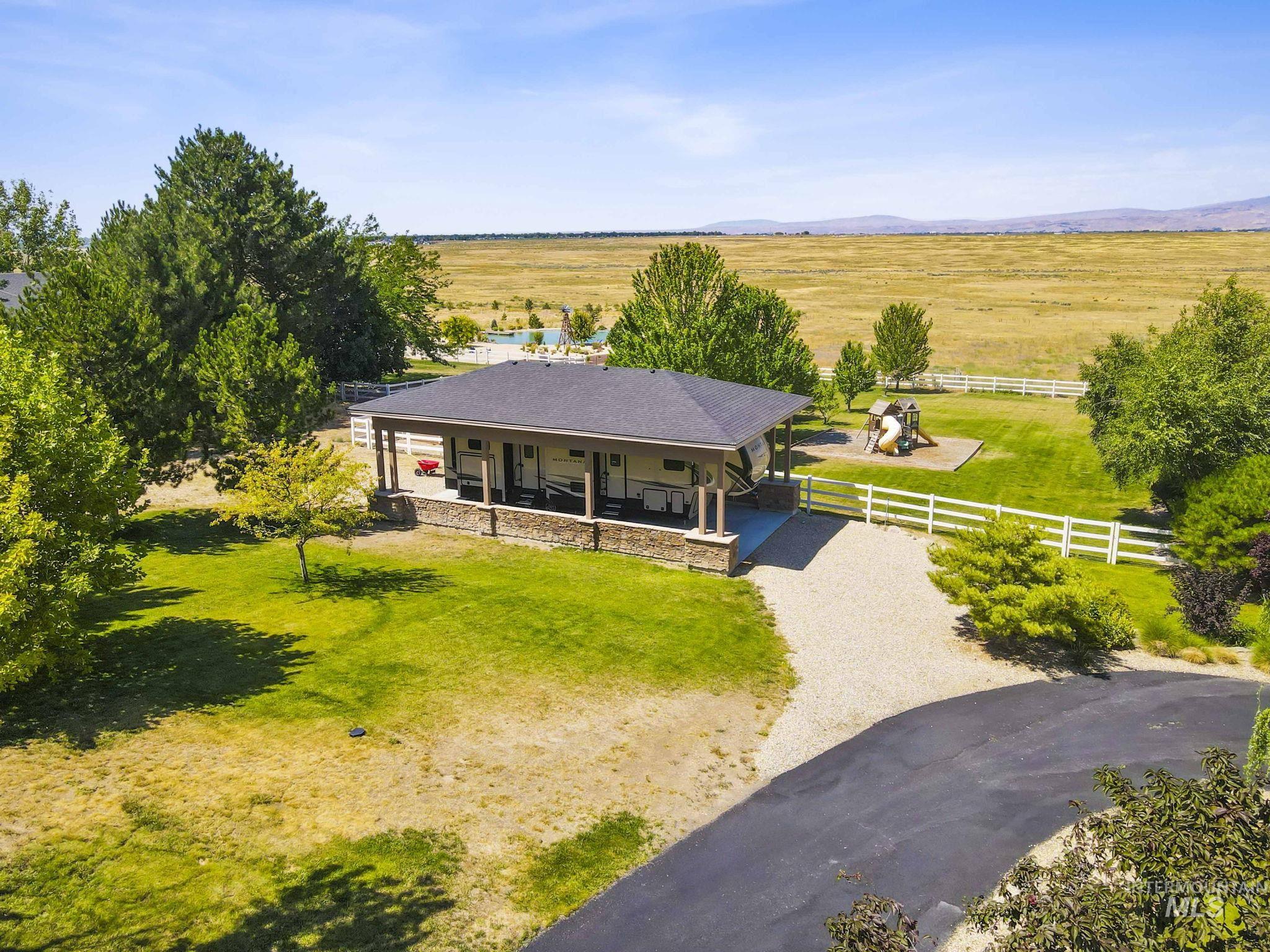 View of front of property featuring a view of rural / pastoral area, covered porch, an attached carport, and gravel driveway