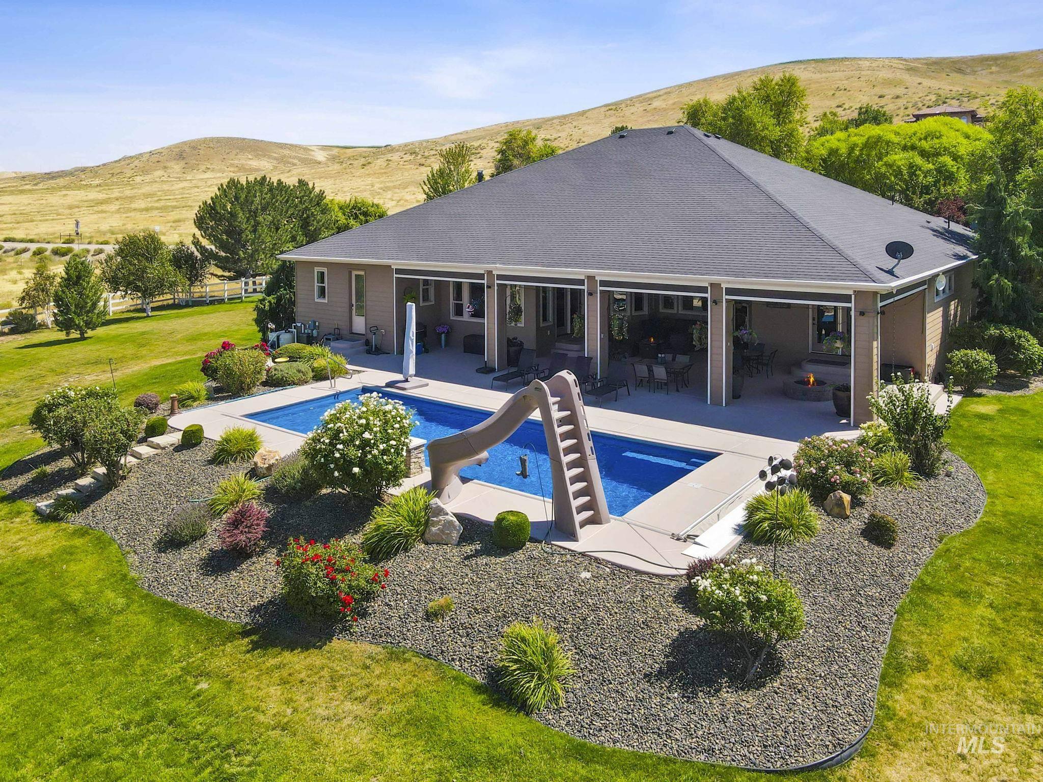 Swimming pool with a water slide, a lawn, a patio, and a mountain view
