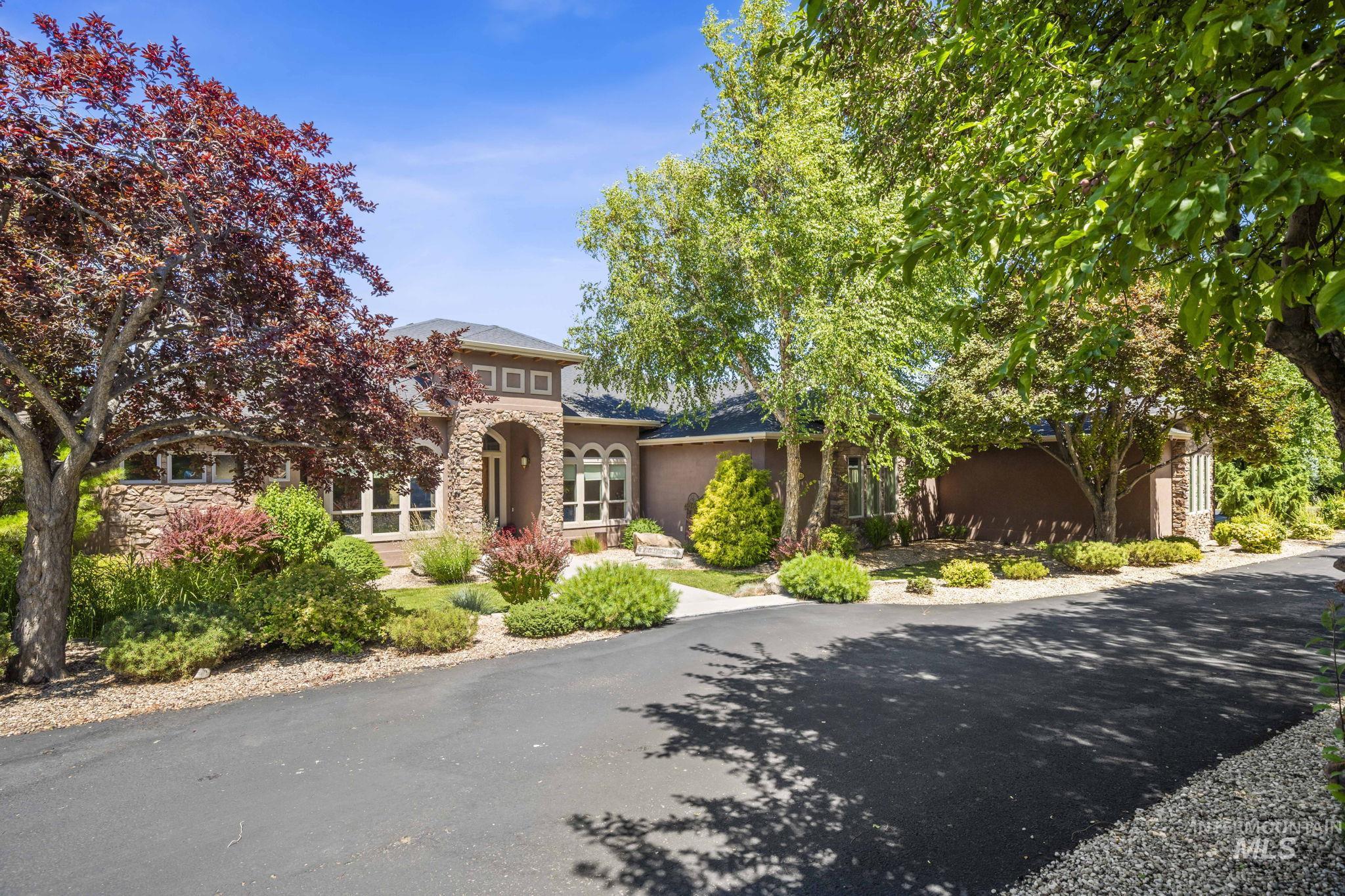 View of front of home with stone siding, asphalt driveway, and stucco siding