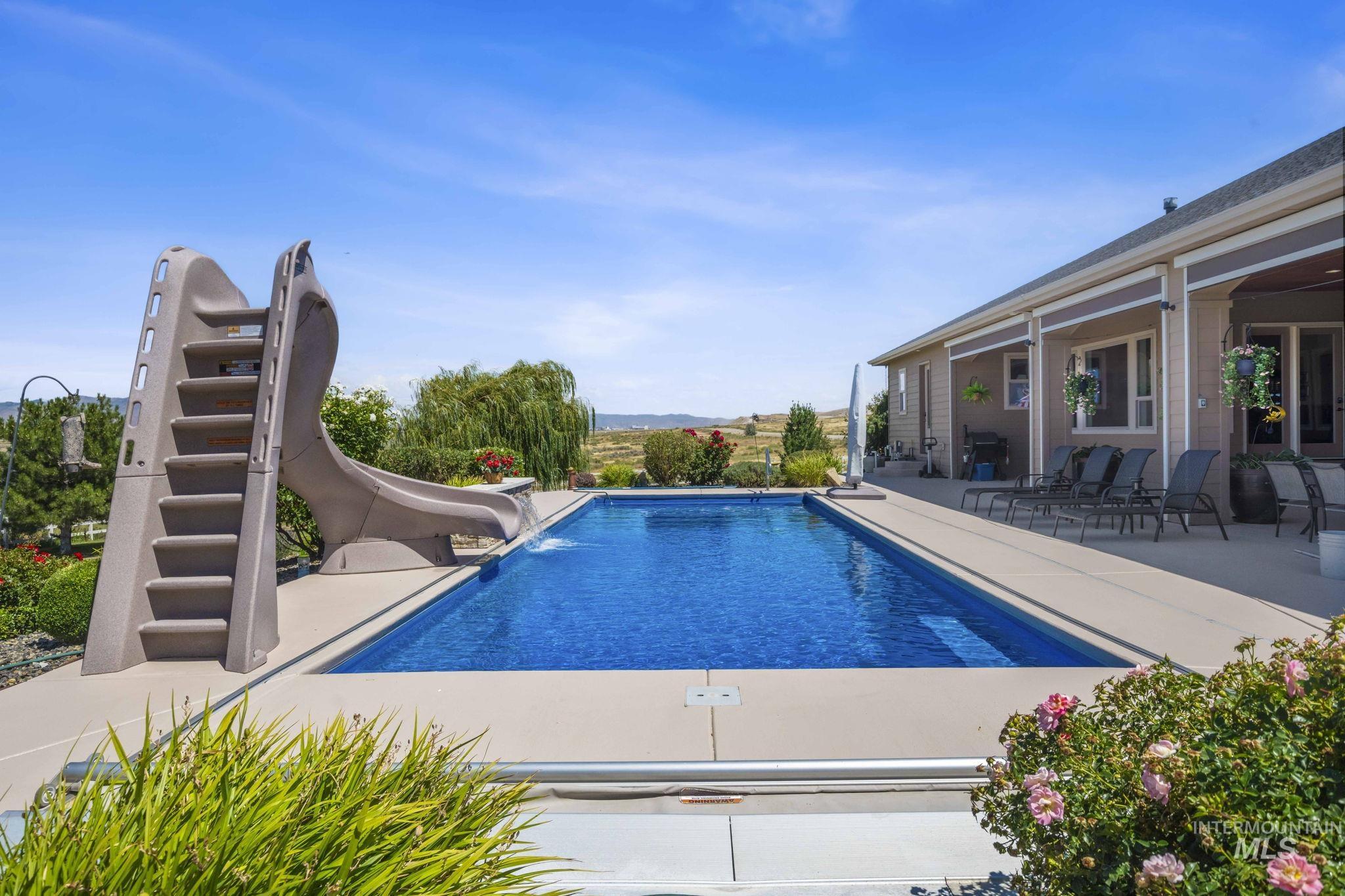 Outdoor pool featuring a water slide and a patio area
