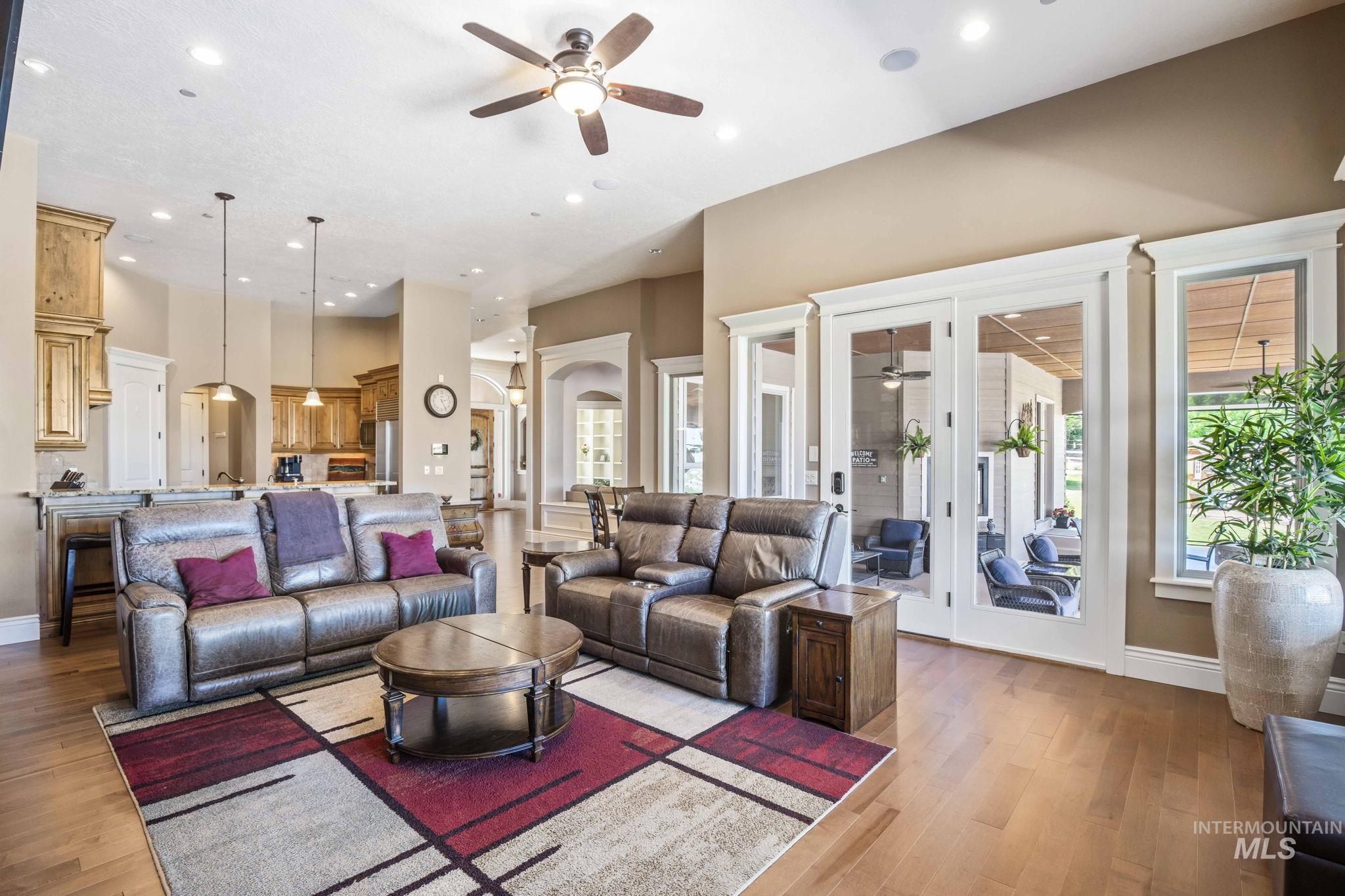 Living room with ceiling fan, arched walkways, recessed lighting, wood finished floors, and plenty of natural light