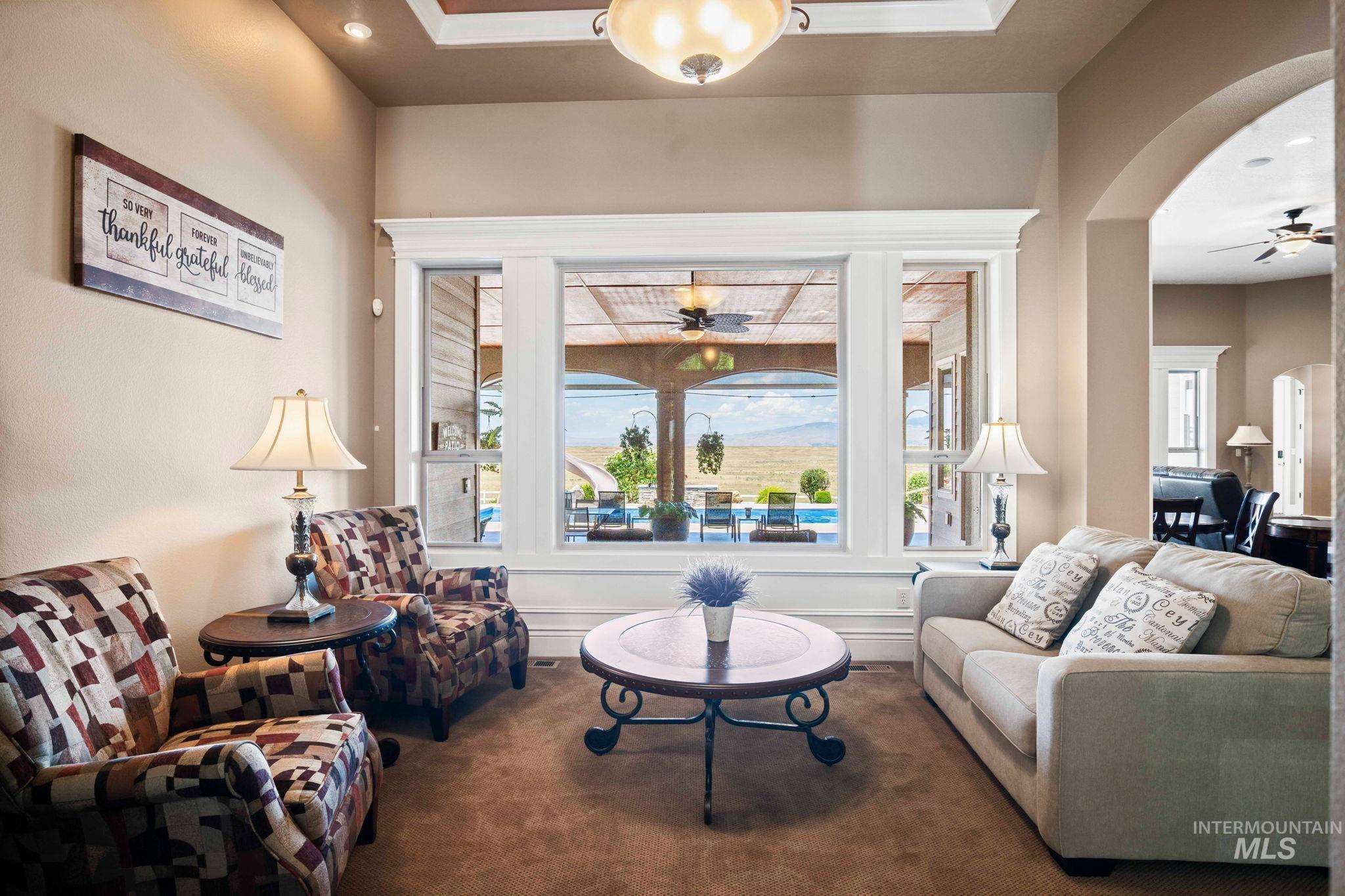 Living area with ceiling fan, arched walkways, and recessed lighting