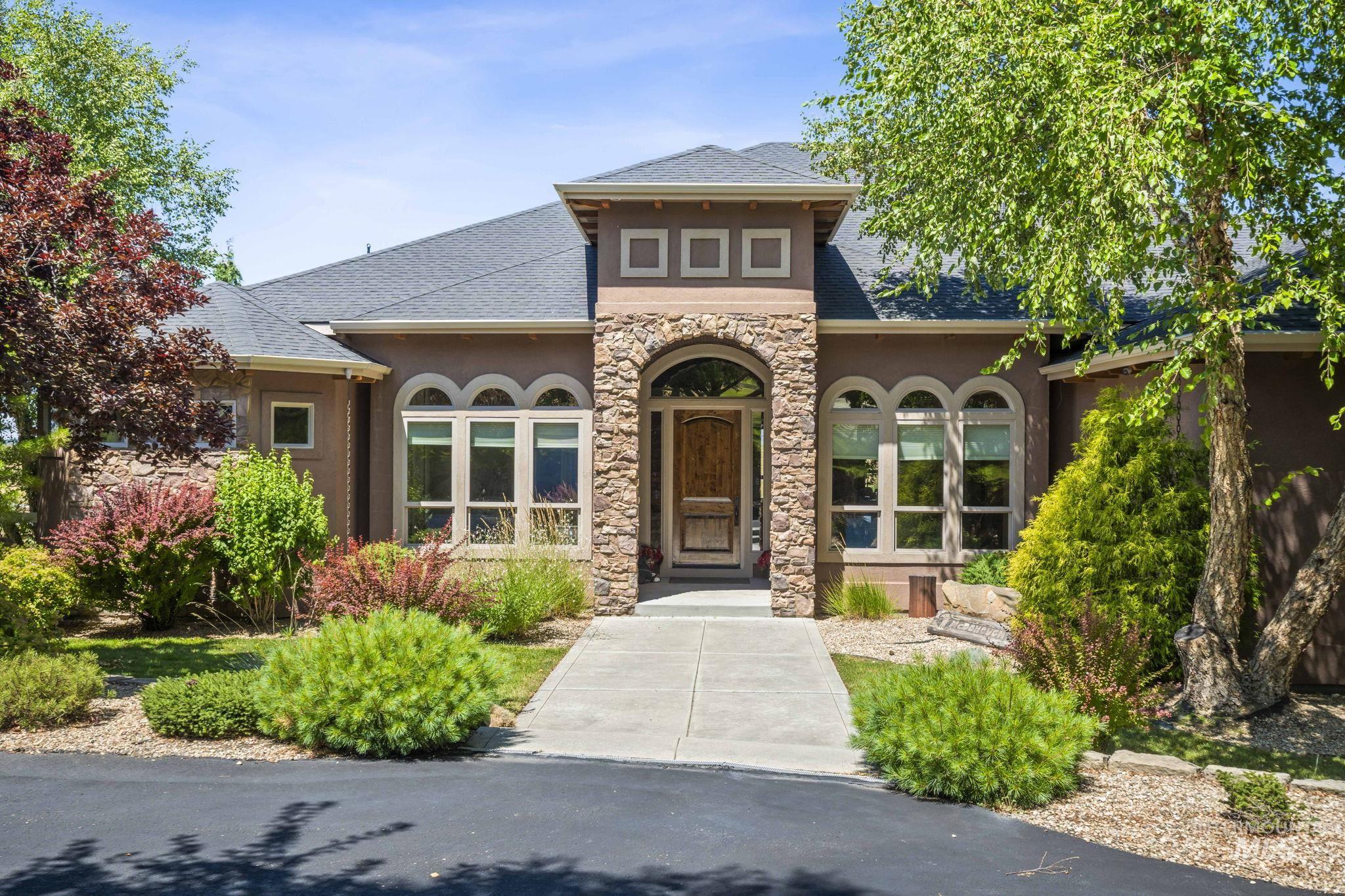 View of front of home featuring stone siding, stucco siding, and roof with shingles