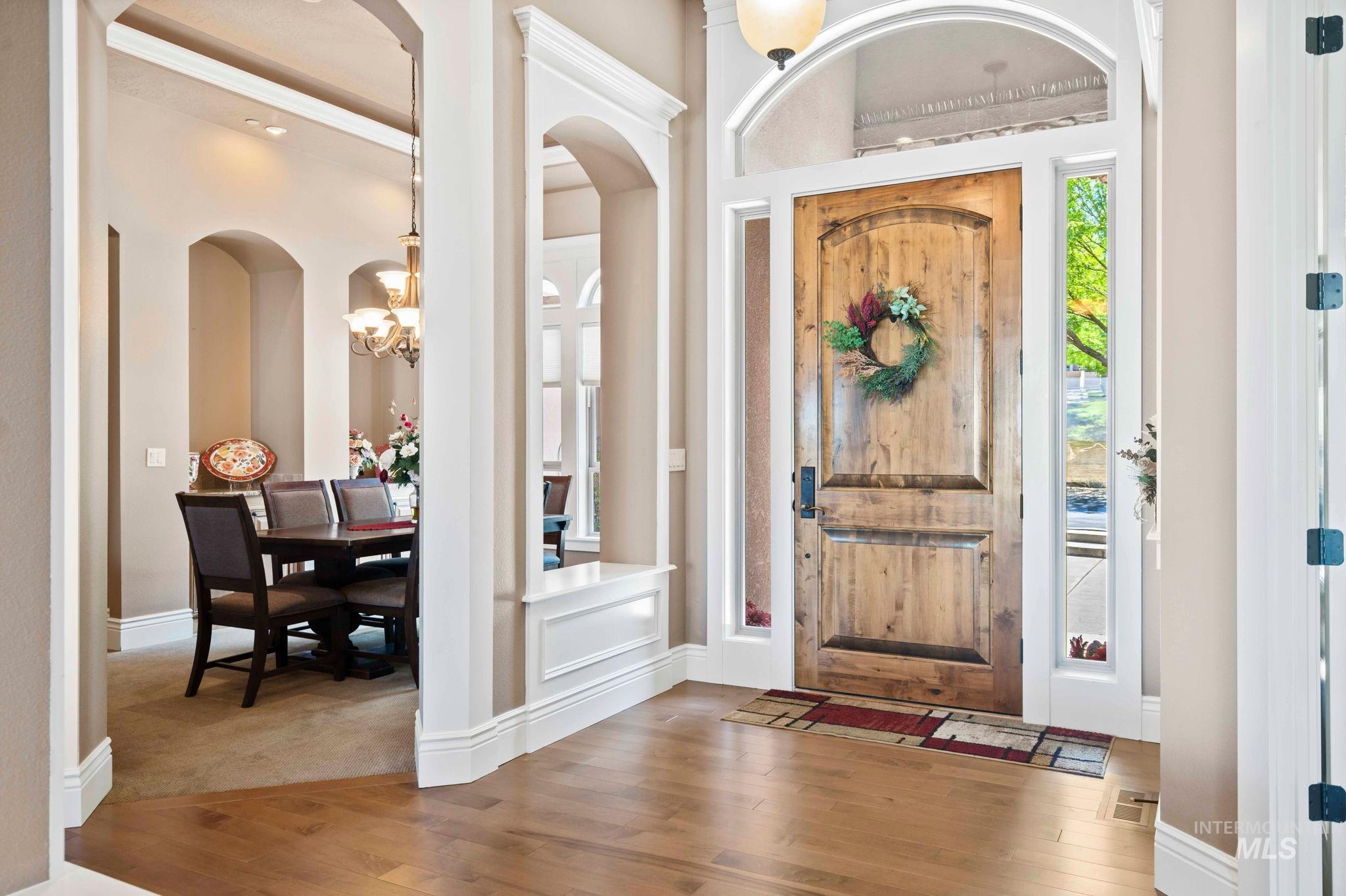 Entrance foyer featuring wood finished floors, arched walkways, and a chandelier