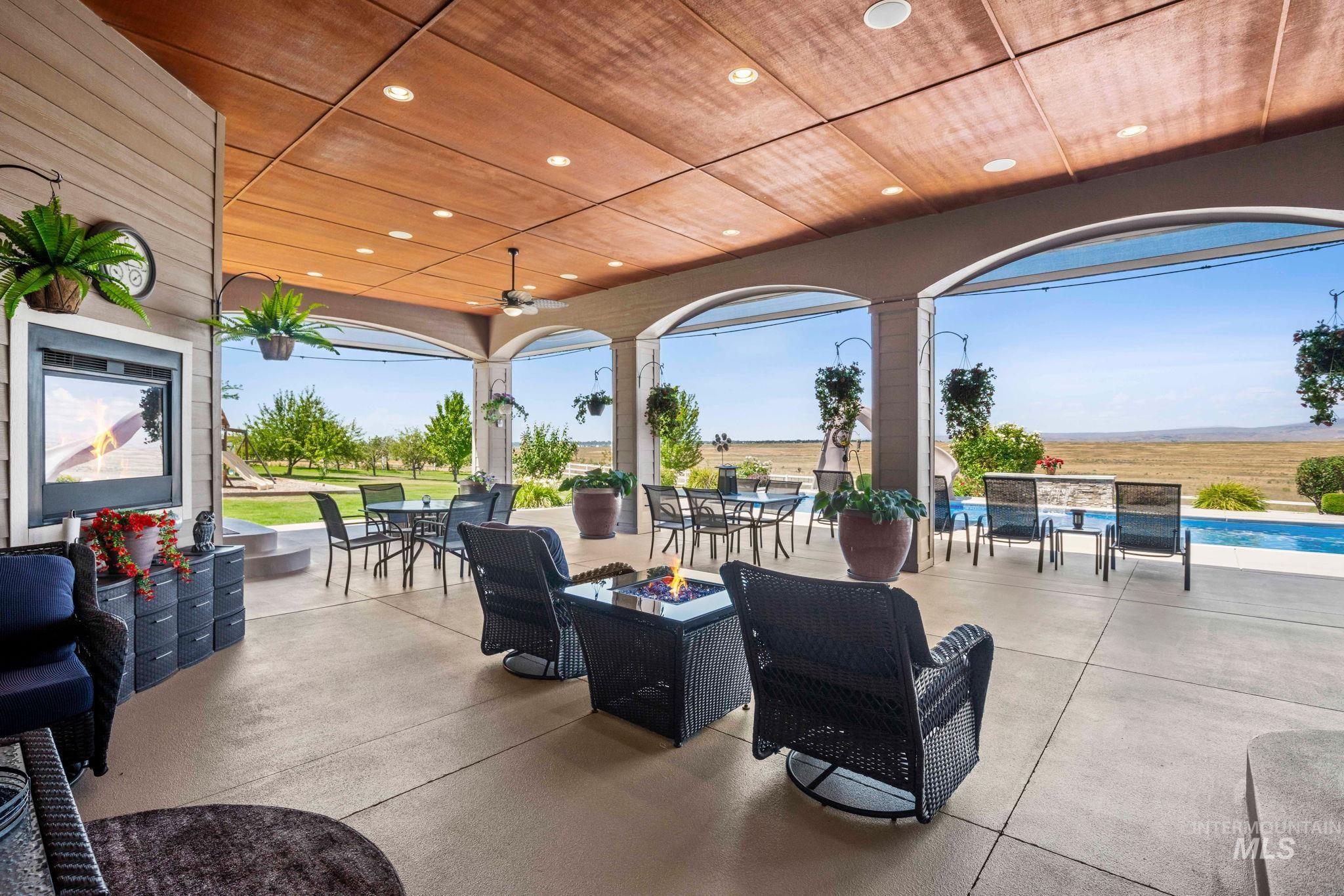 View of patio featuring outdoor dining area, a fire pit, an outdoor pool, and ceiling fan